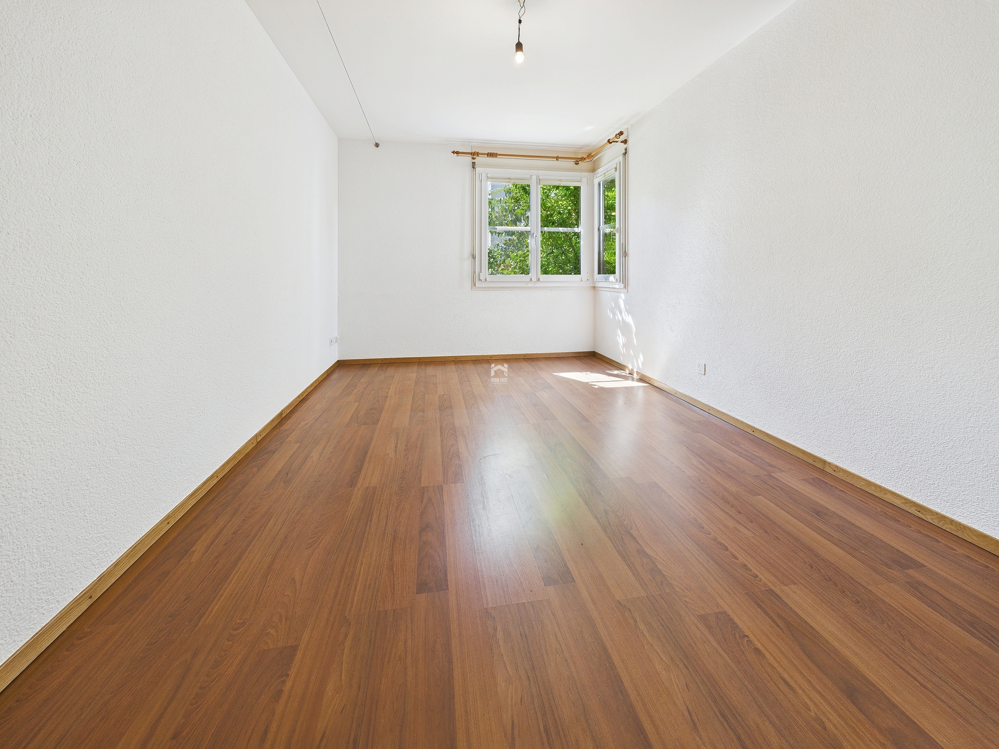 Leerer heller Raum mit Holzoptikboden und Fenster