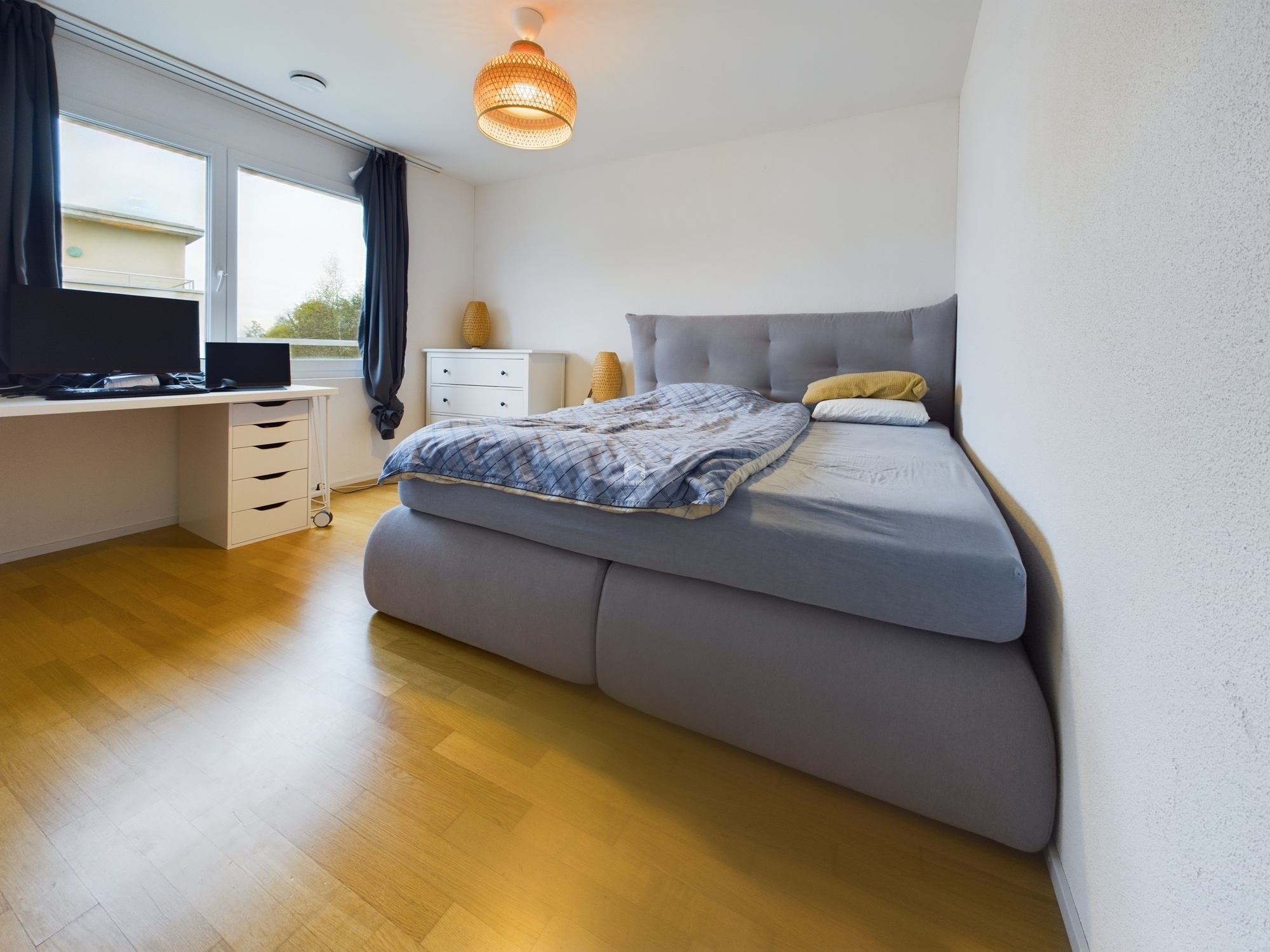 Helles Schlafzimmer mit Bett und Arbeitsbereich