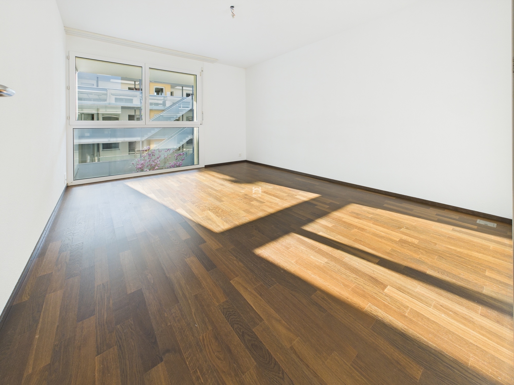 Leerer, sonnendurchfluteter Raum mit großem Fenster