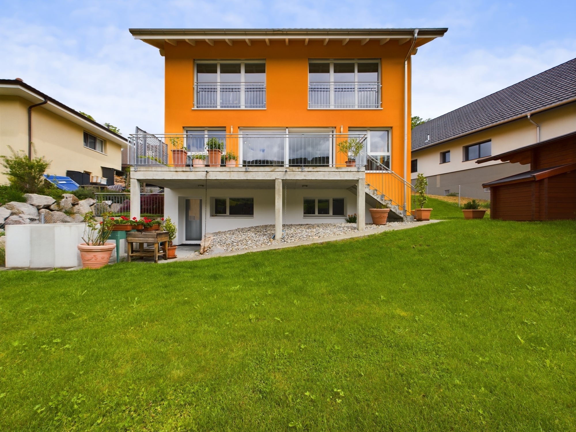 Modernes Einfamilienhaus mit orangefarbener Fassade und großem Garten