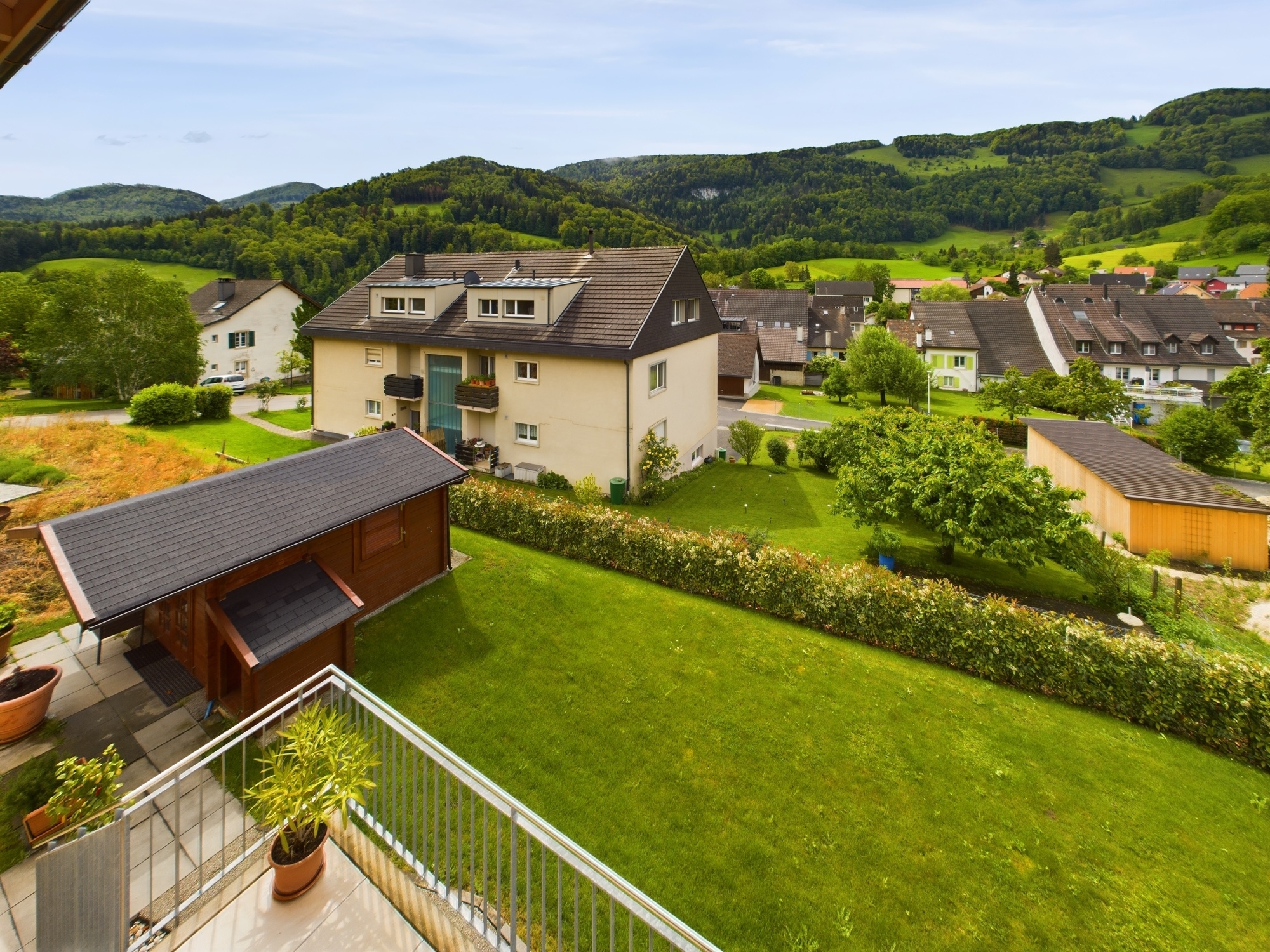 Balkonblick auf Wohnhäuser und grüne Hügellandschaft