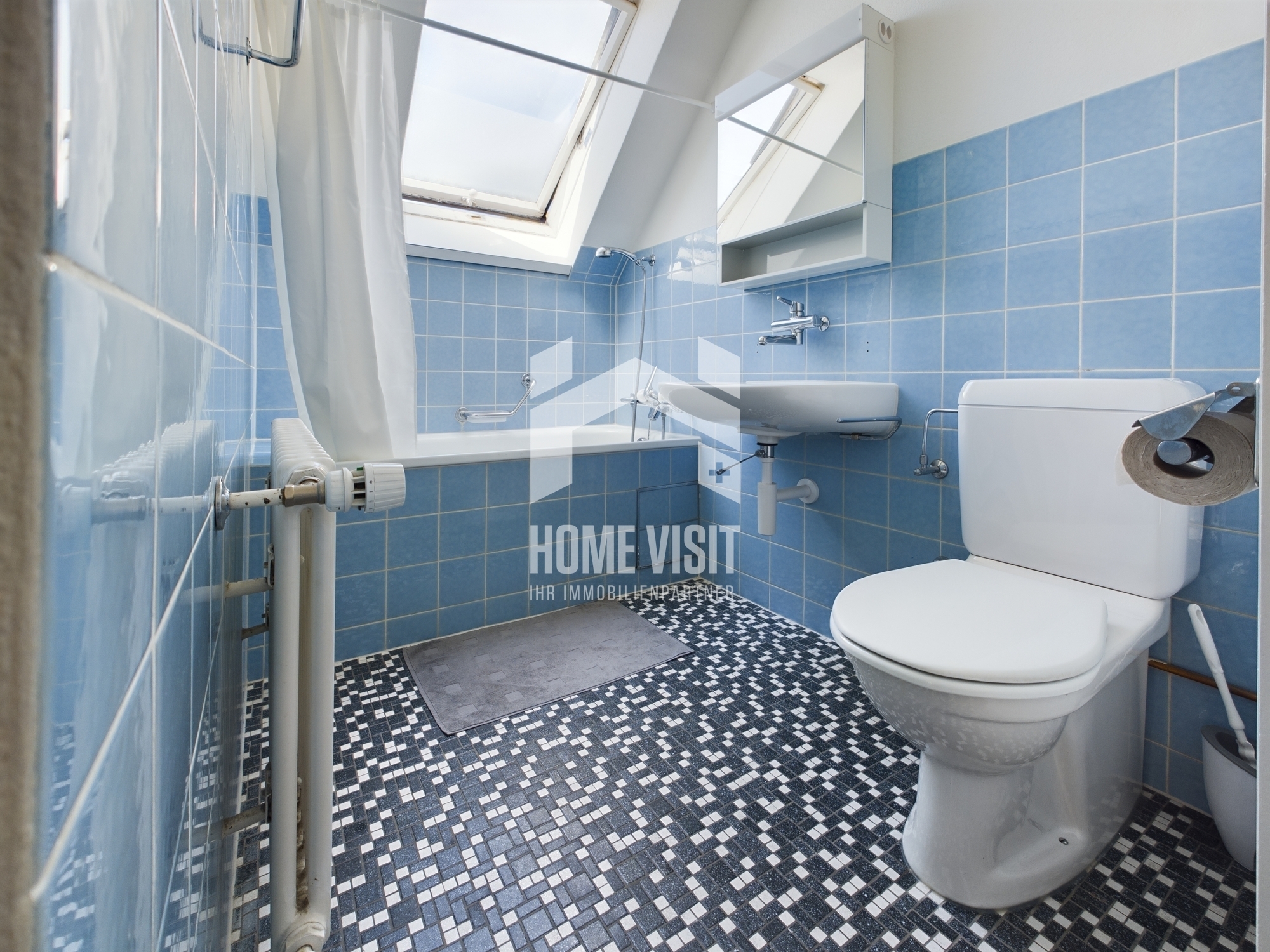 Badezimmer mit blau gefliesten Wänden und Dachfenster