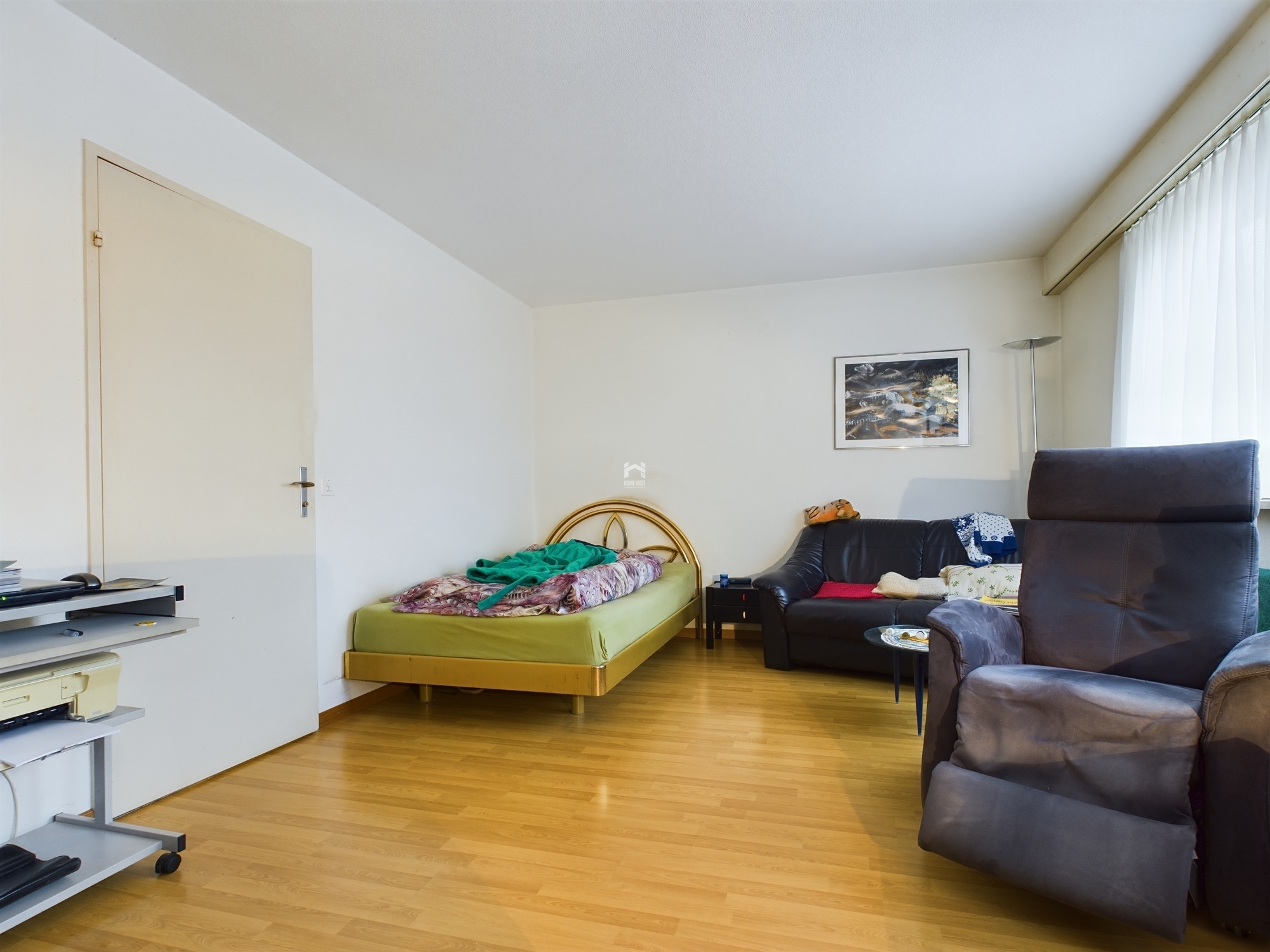 Helles, schlicht möbliertes Zimmer mit Bett und Sitzbereich