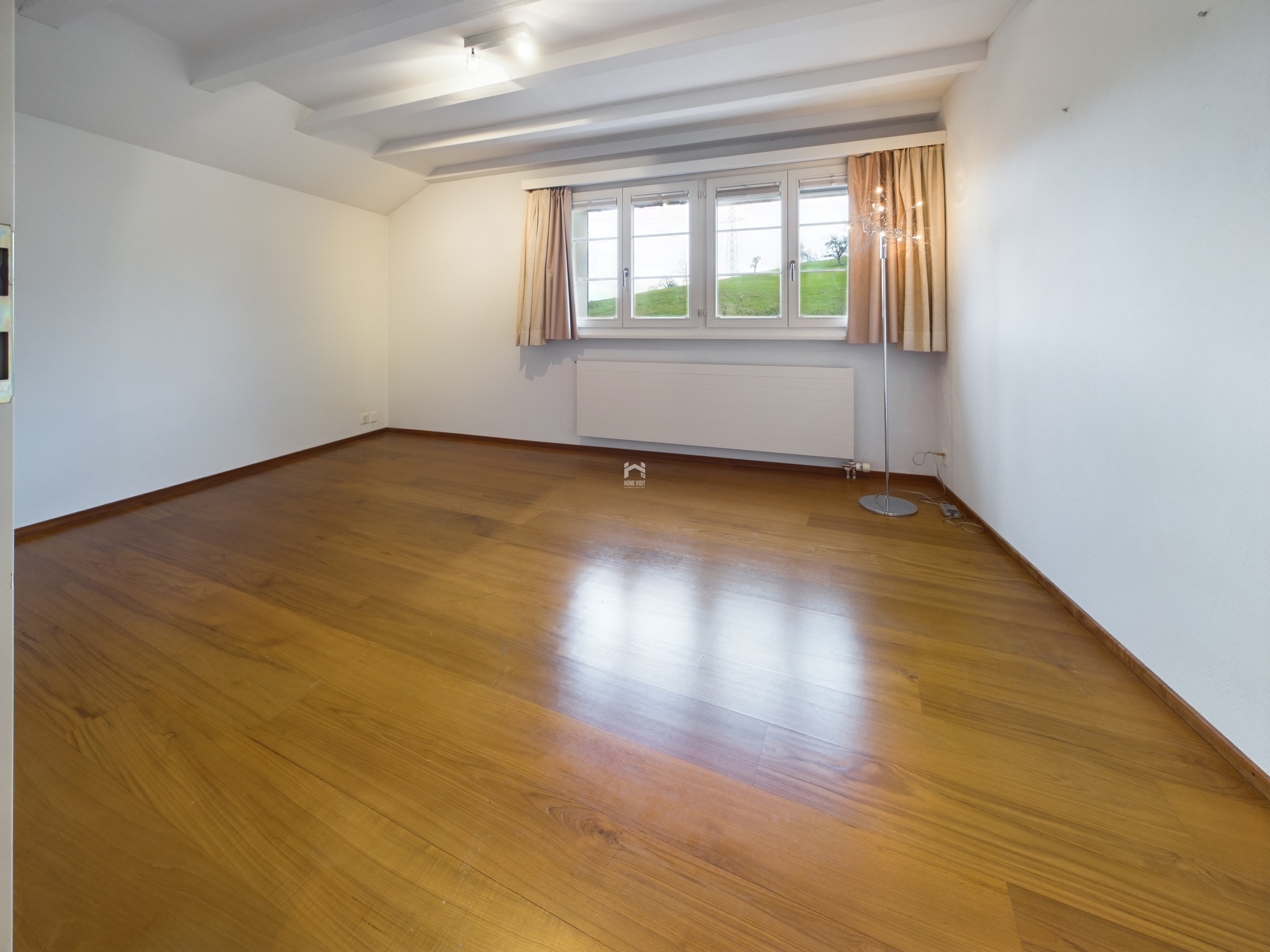 Leerer Wohnraum mit Parkettboden und Fensterfront