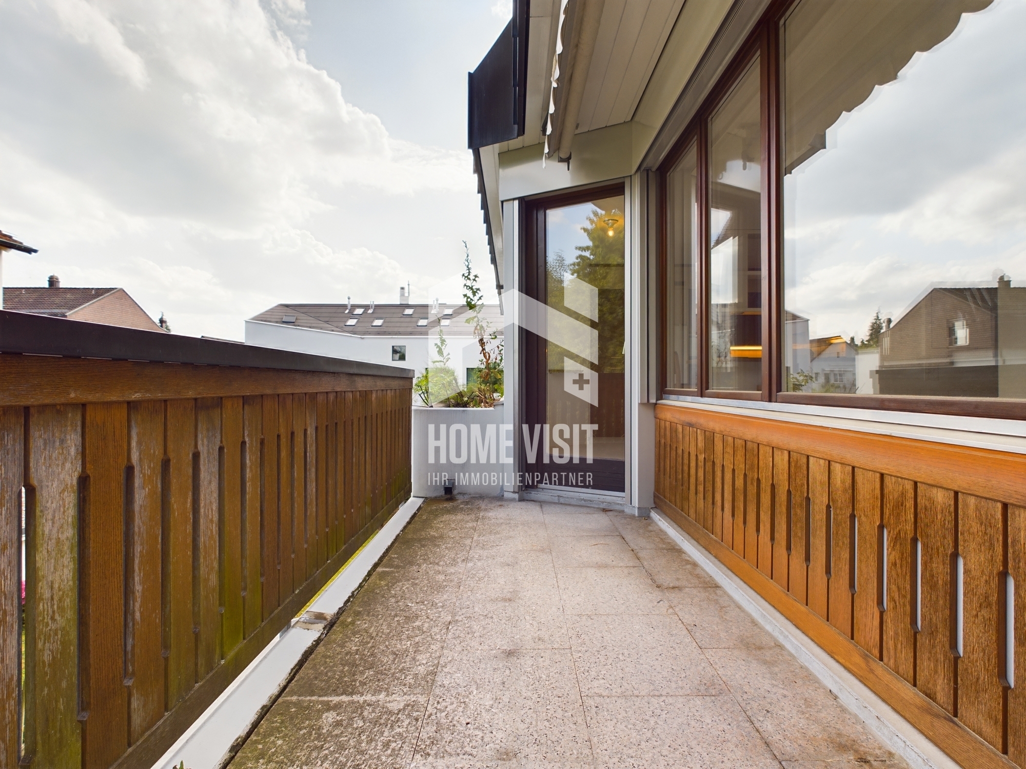 Balkon mit Holzgeländer und Nachbarschaftsblick
