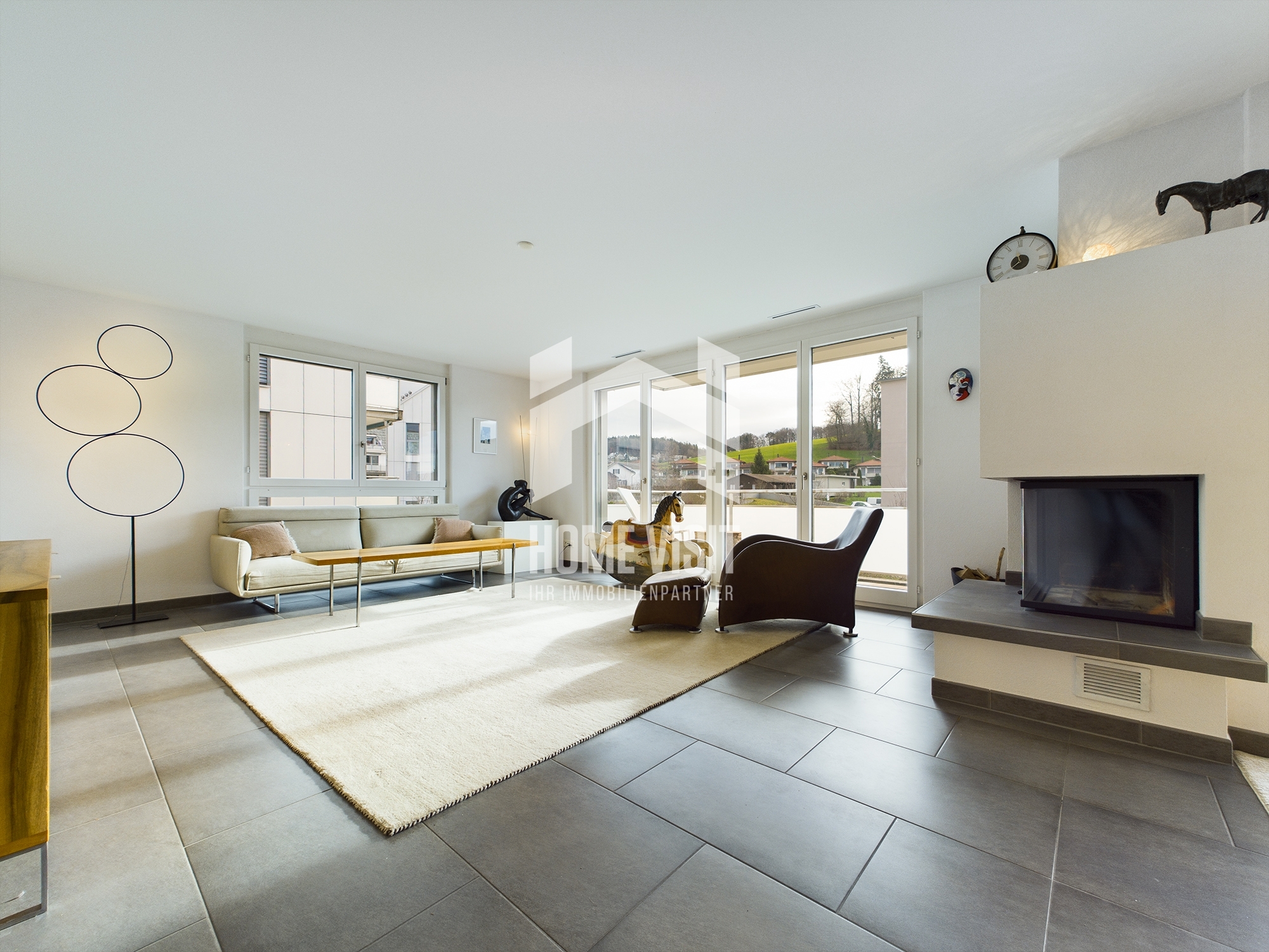 Helles Wohnzimmer mit Kamin und Balkonblick