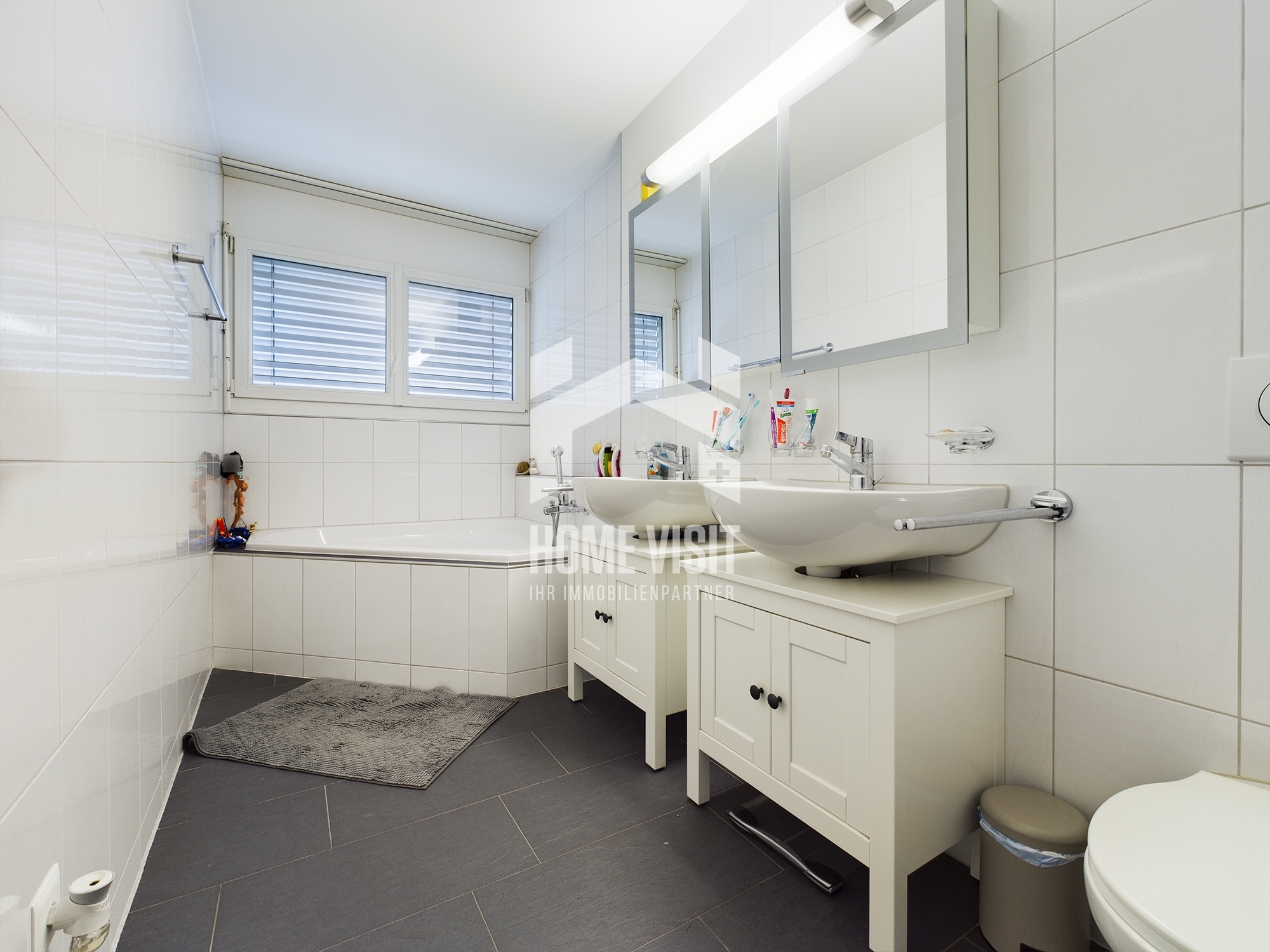 Helles Badezimmer mit Doppelwaschtisch und Badewanne