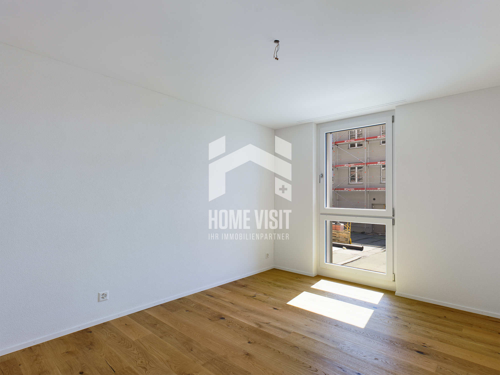 Heller leerer Wohnraum mit Parkett und Fenster