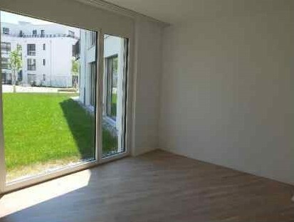 Heller leerer Wohnraum mit großer Fensterfront zum Garten
