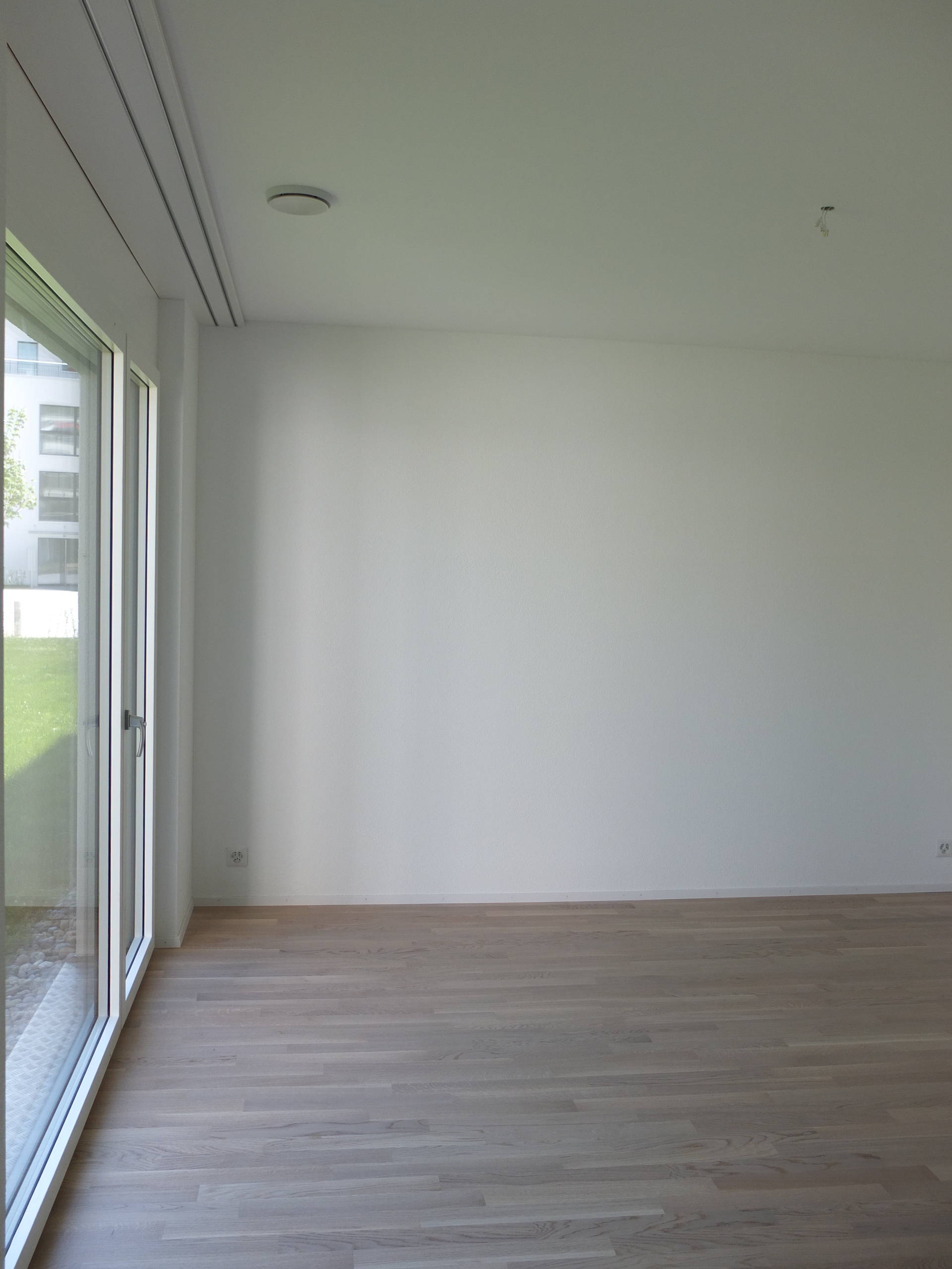 Leerer heller Wohnraum mit bodentiefen Fenstern