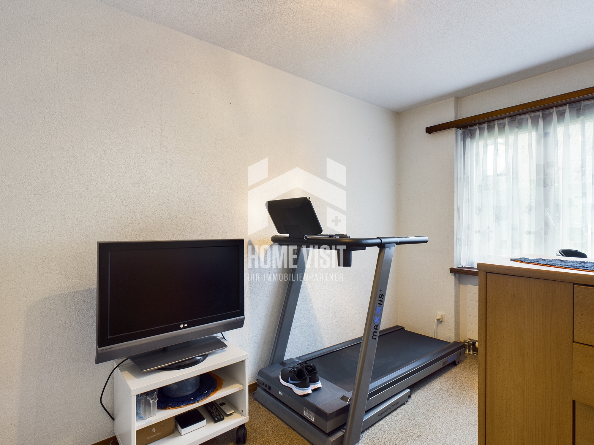 Fitnessraum mit Laufband und Fernseher