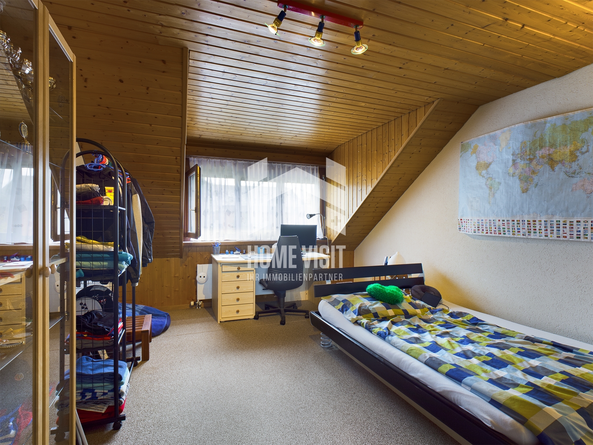 Dachzimmer mit Bett und Arbeitsbereich