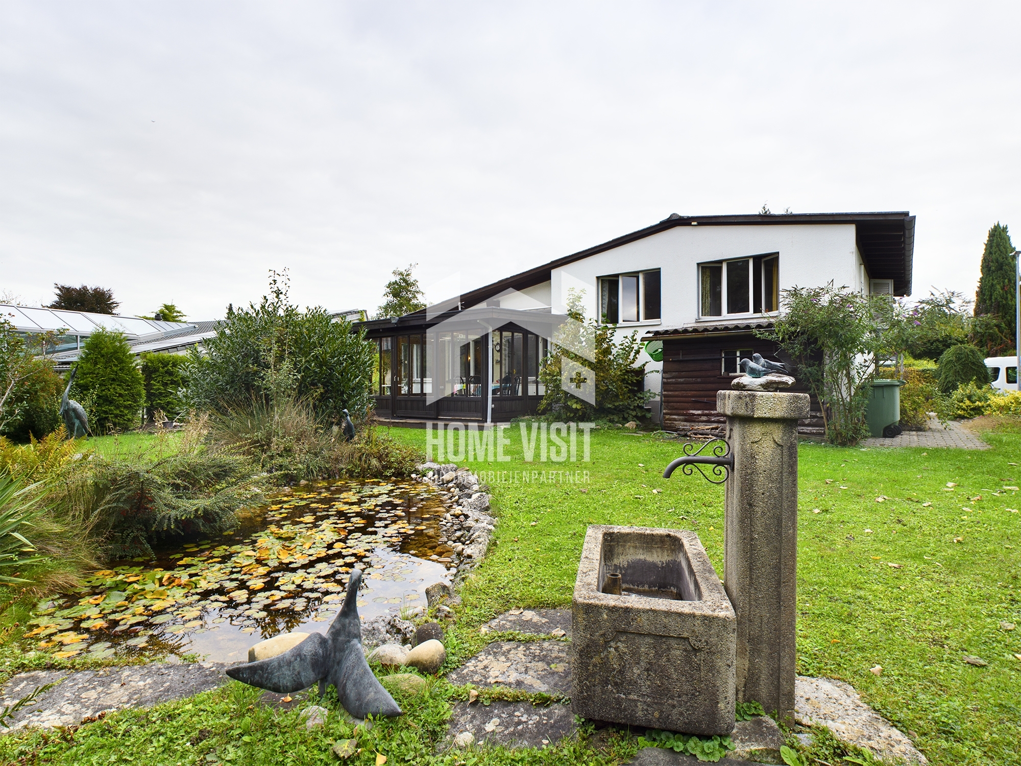 Gartenansicht mit Einfamilienhaus und Teich