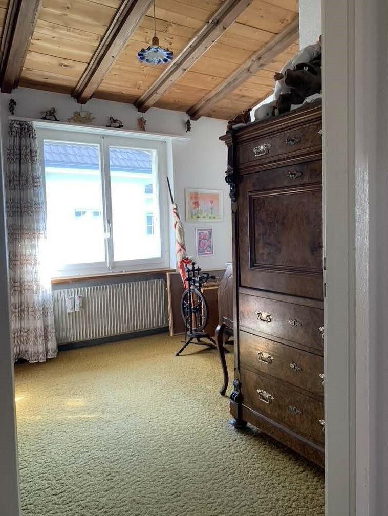 Gemütliches Dachzimmer mit Teppich und antikem Schrank