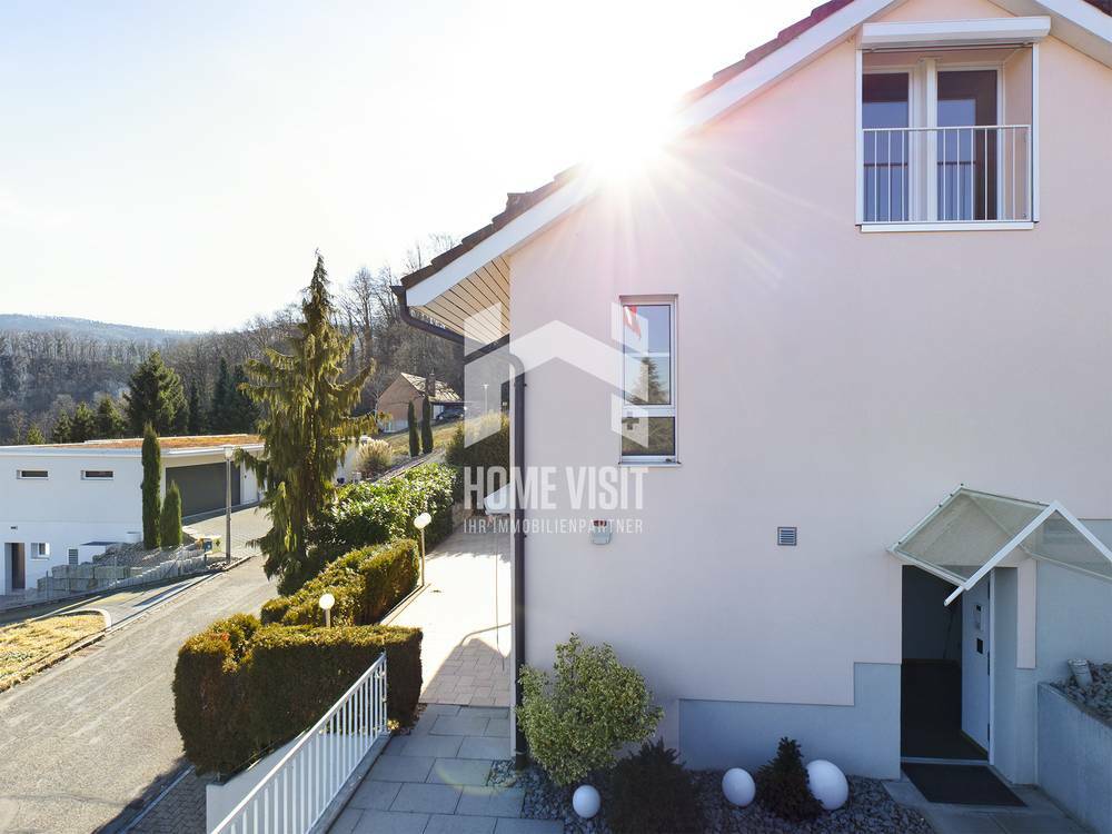 Außenansicht eines Einfamilienhauses mit sonnigem Hanggrundstück