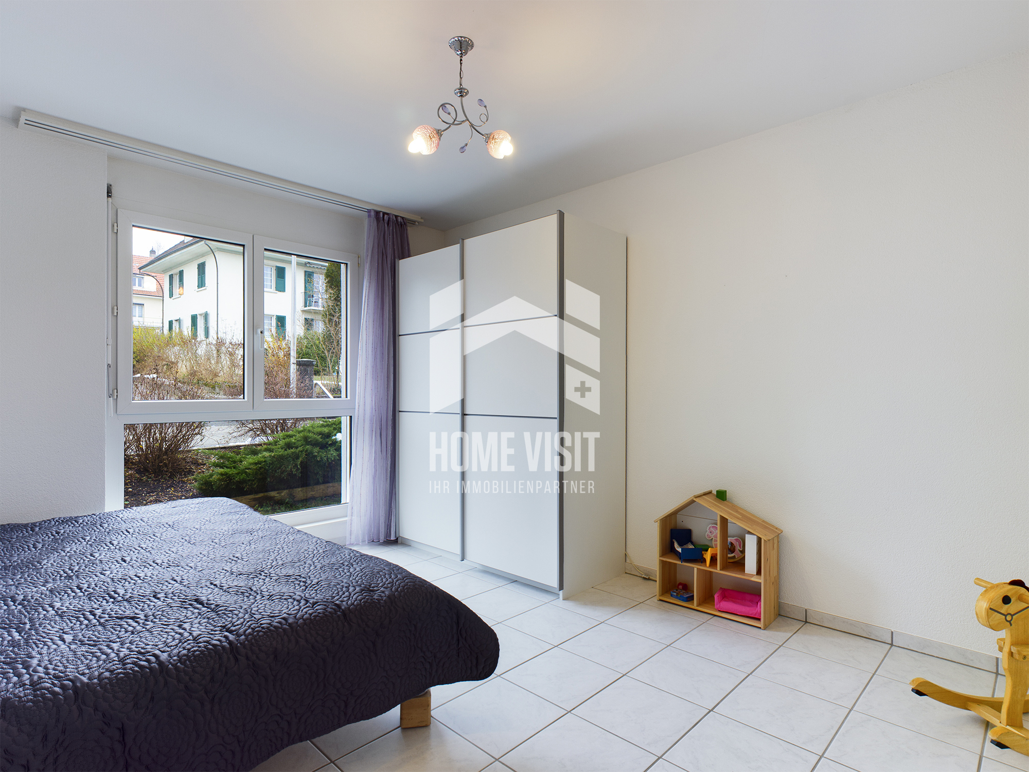Helles Schlafzimmer mit großem Fenster und Schrank