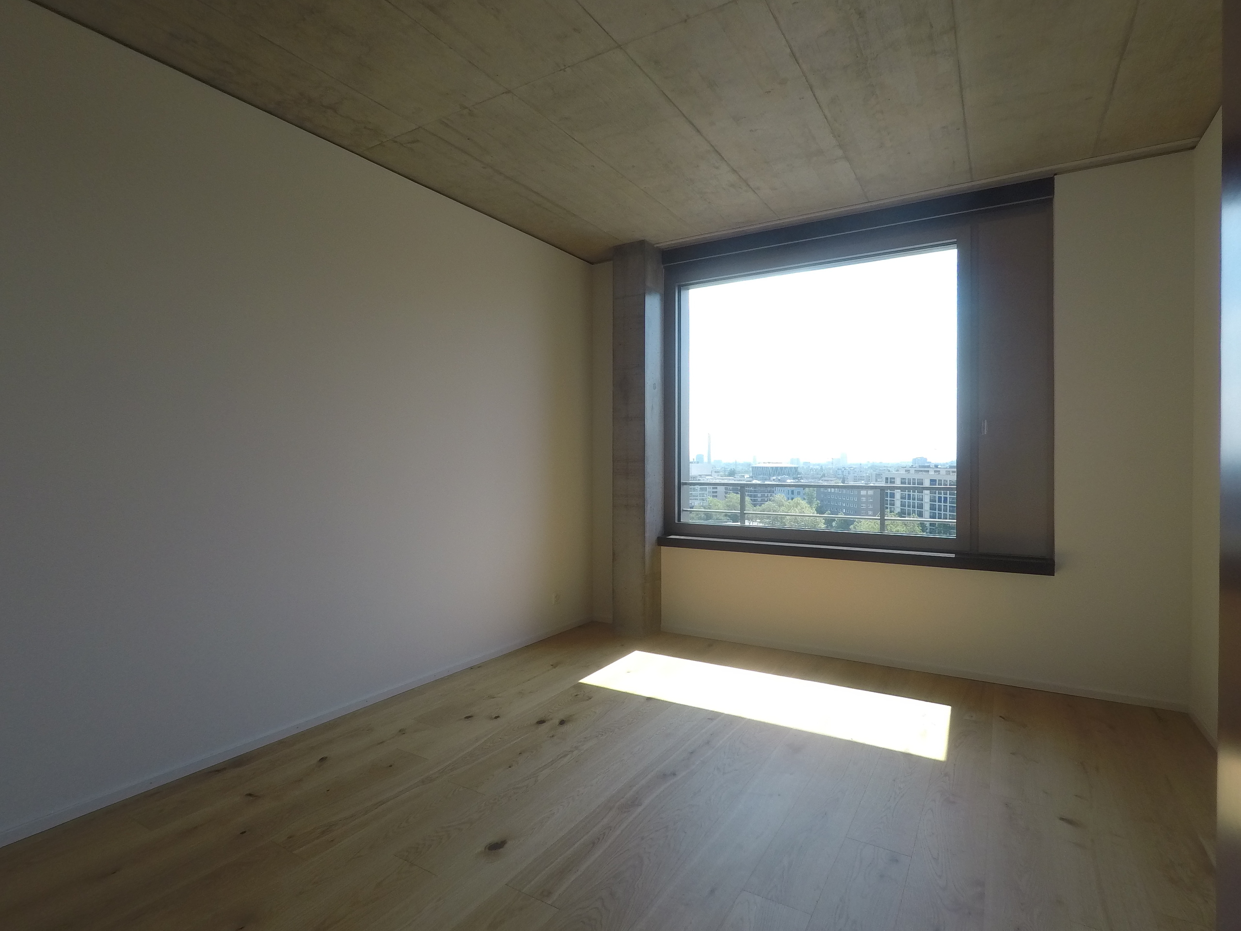 Leerer, moderner Wohnraum mit großem Fenster und Stadtblick