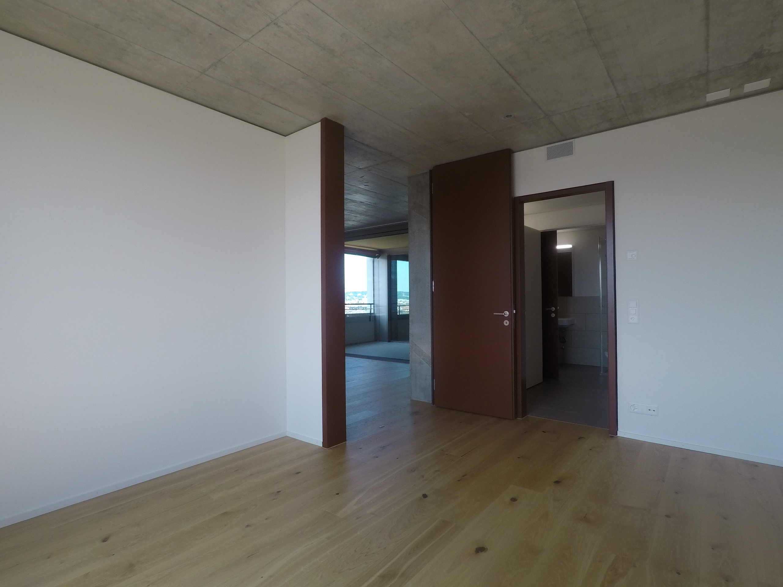 Modernes, leeres Zimmer mit Beton-Decke und Holzboden