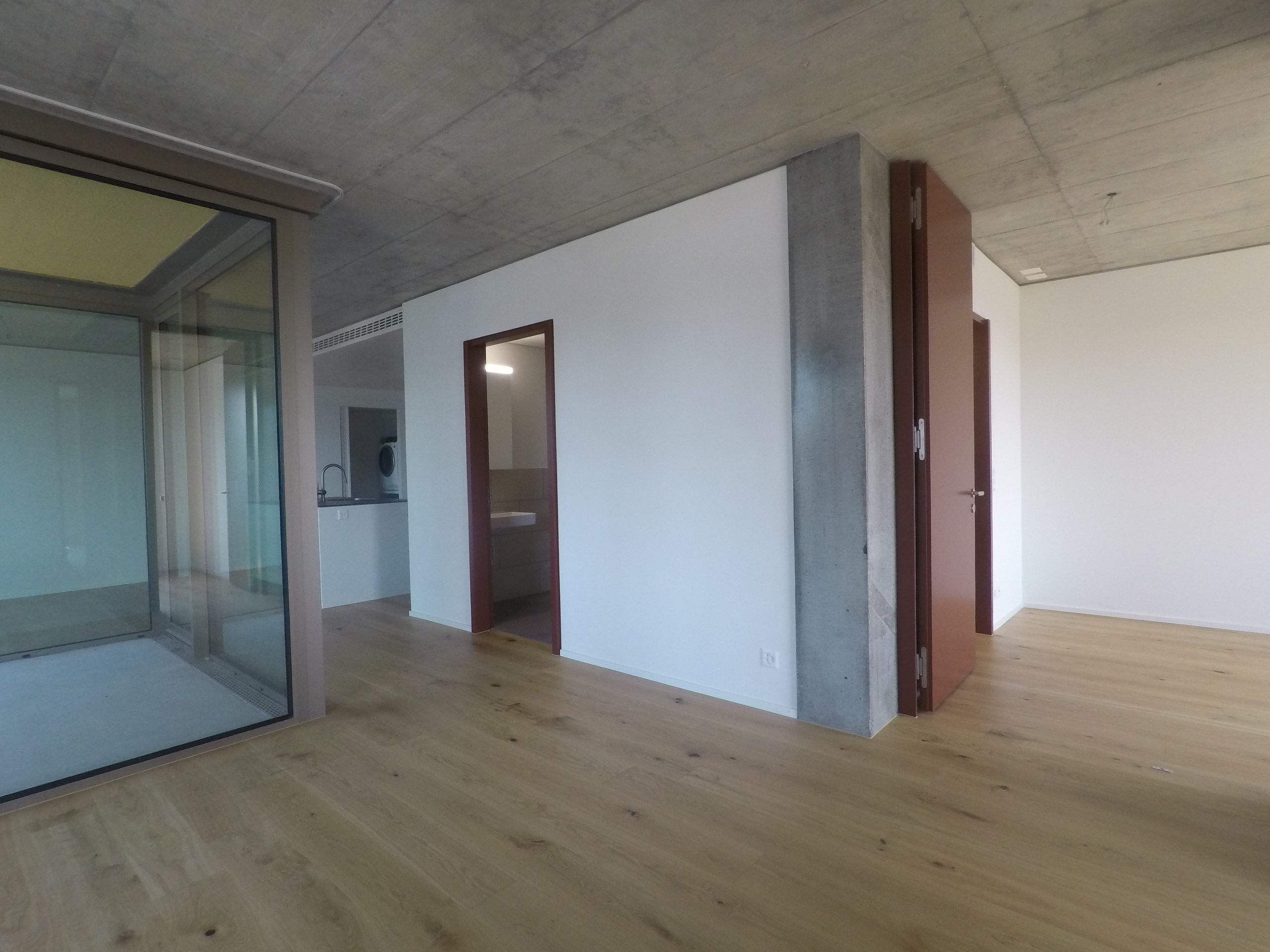 Modernes, leeres Innenraumfoto mit Betondecke und Holzboden