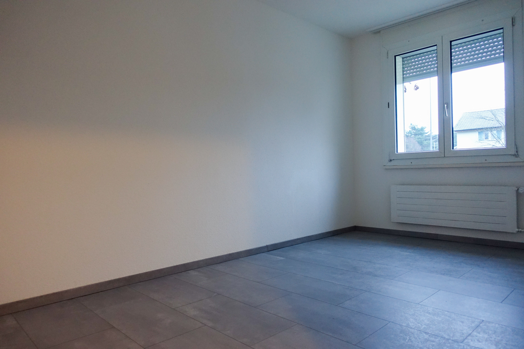 Leerer, heller Innenraum mit Fenster und Heizkörper