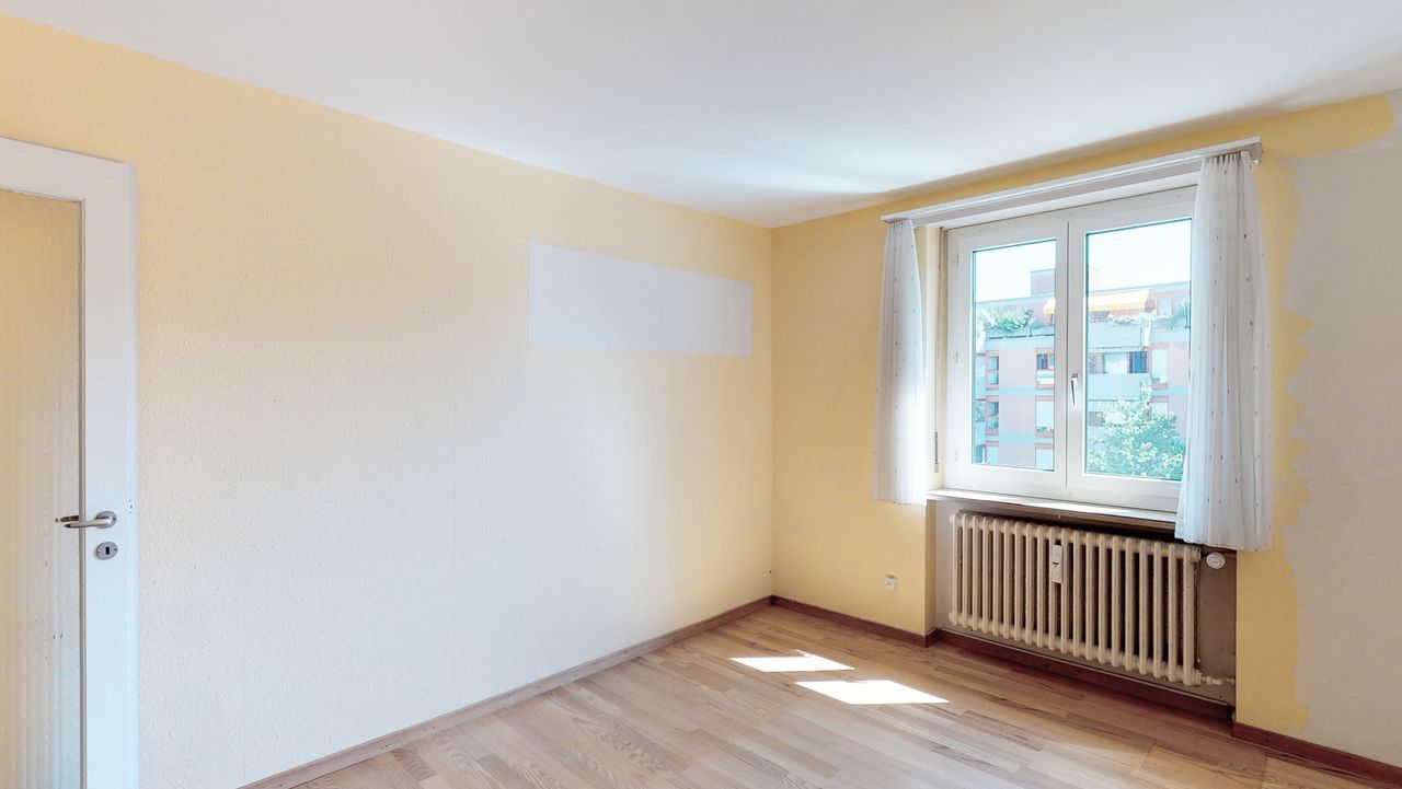 Leerer heller Wohnraum mit Fenster und Heizkörper