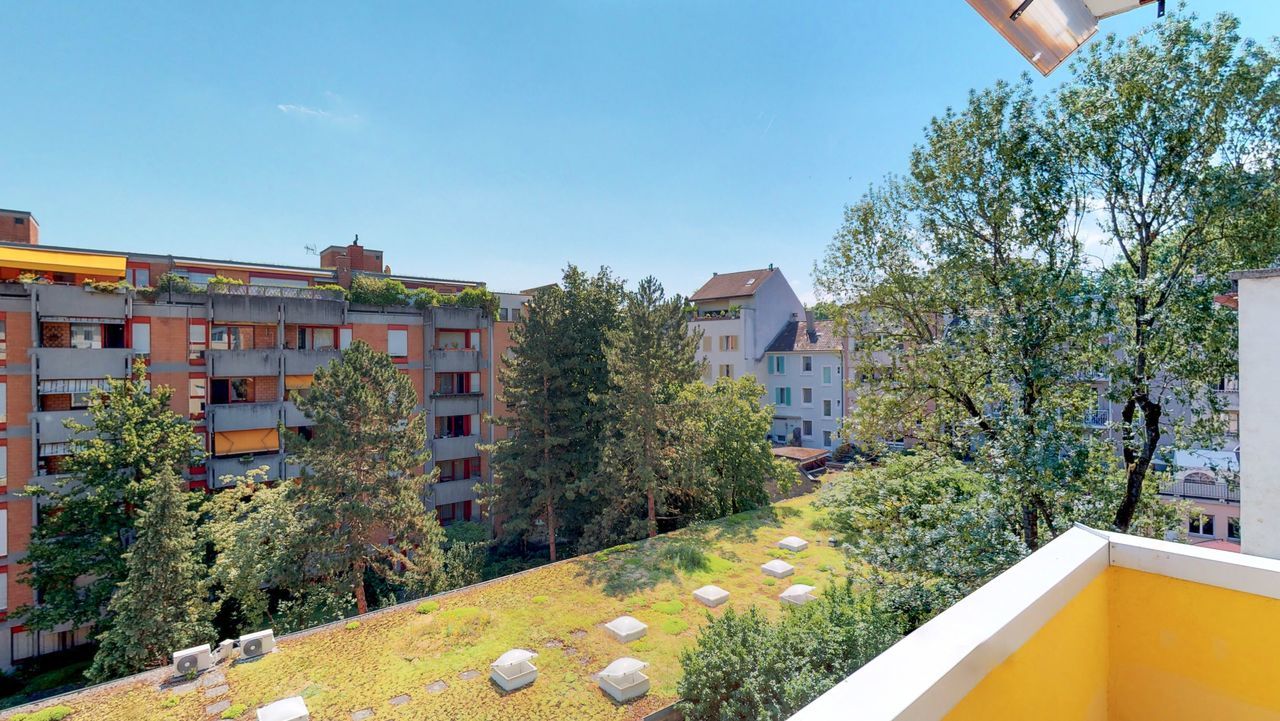 Balkon mit Blick ins Grüne und auf Nachbargebäude