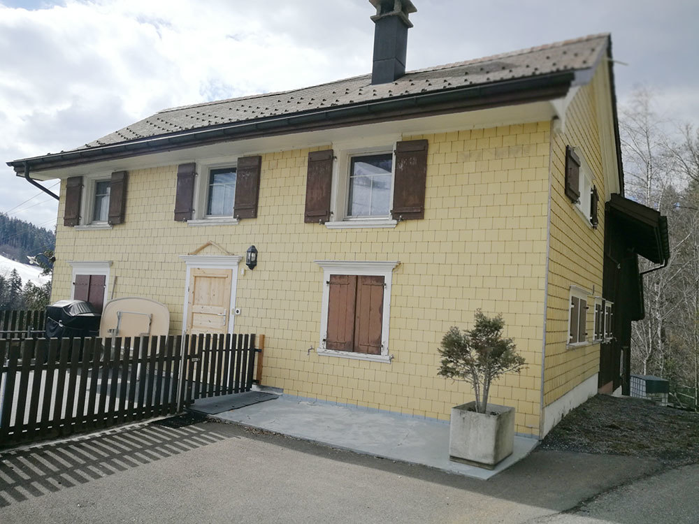 Außenansicht eines gelb verschindelten Hauses