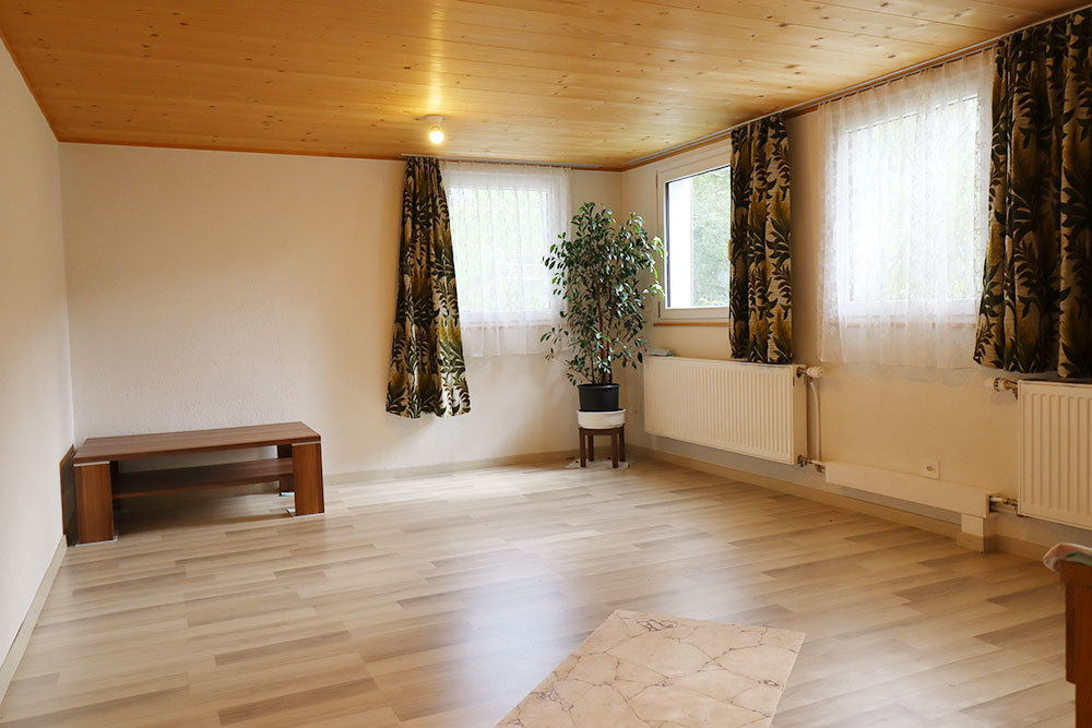 Heller leerer Wohnraum mit Holzdecke und Fensterfront