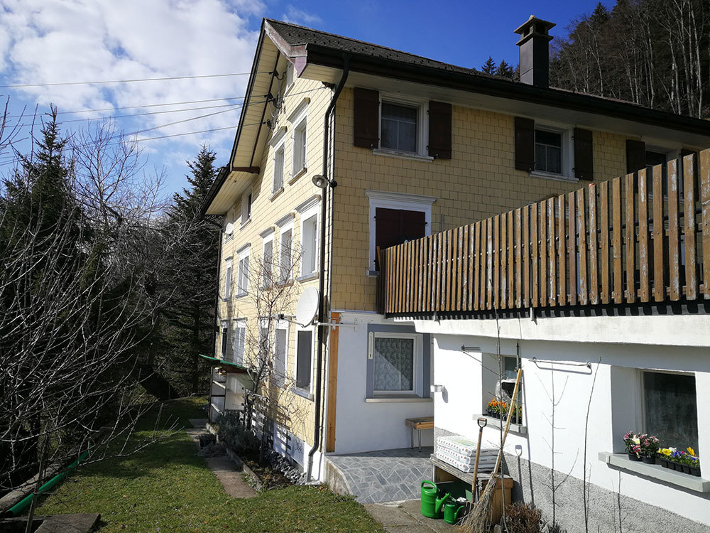 Außenansicht eines Wohnhauses mit Balkon und Garten