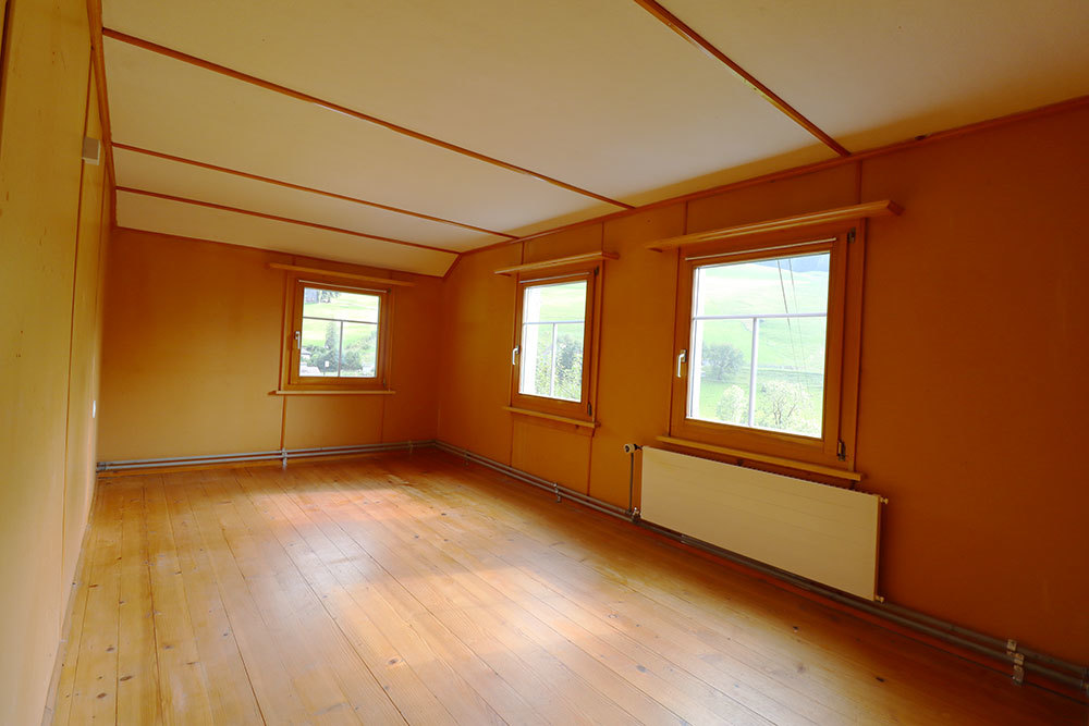 Leerer Raum mit Holzfußboden und drei Fenstern