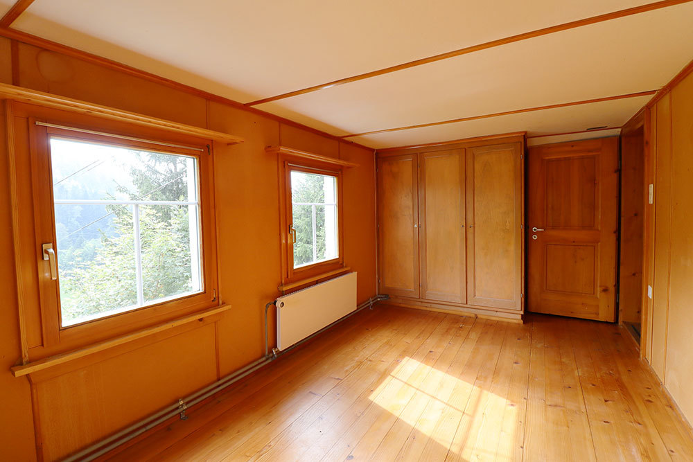 Holzvertäfeltes Zimmer mit Fenstern und Einbauschrank