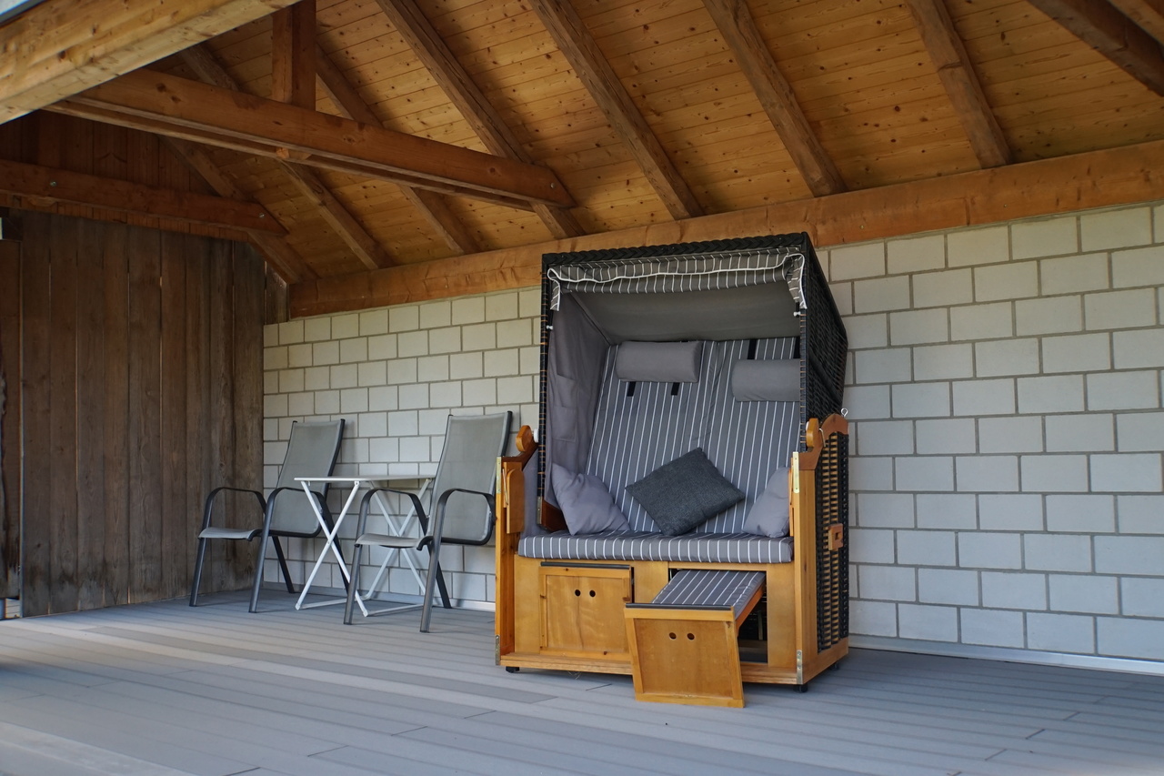 Überdachte Holzterrasse mit Sitzmöbeln