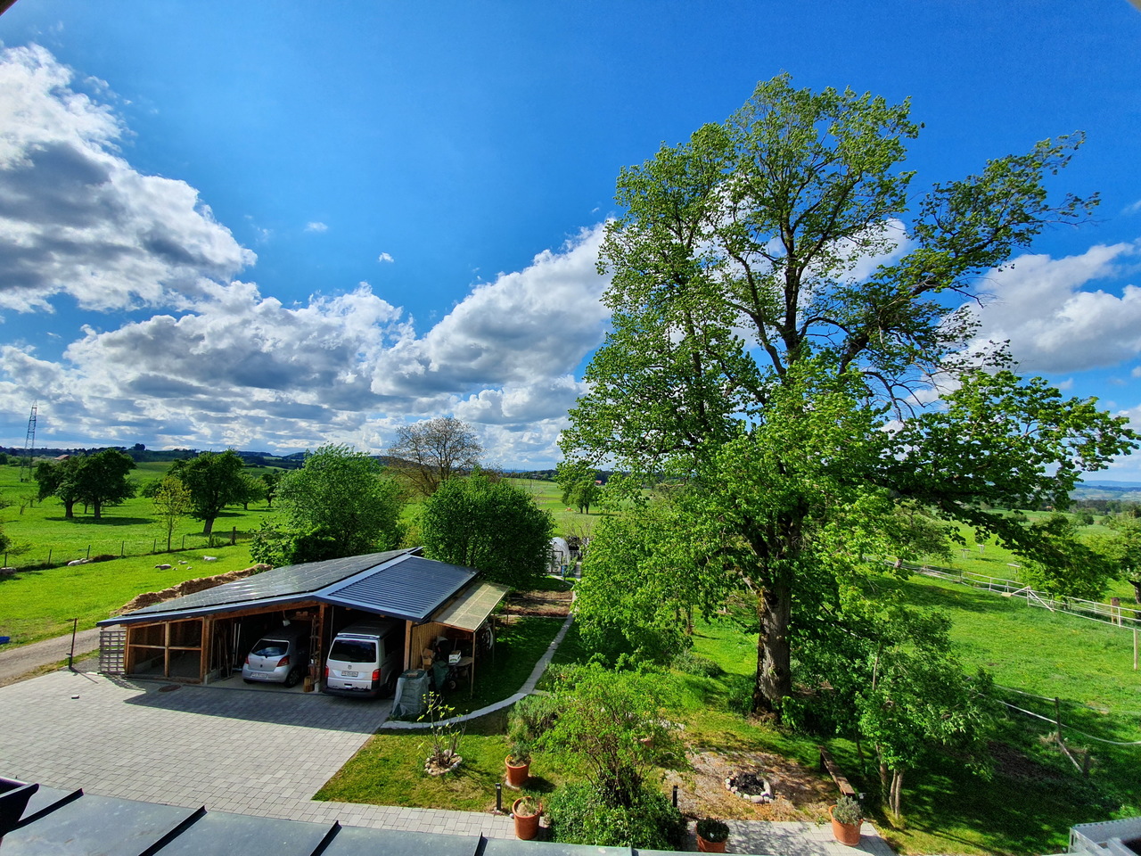 Ländliche Grundstücksansicht mit Carport und weitem Grünblick