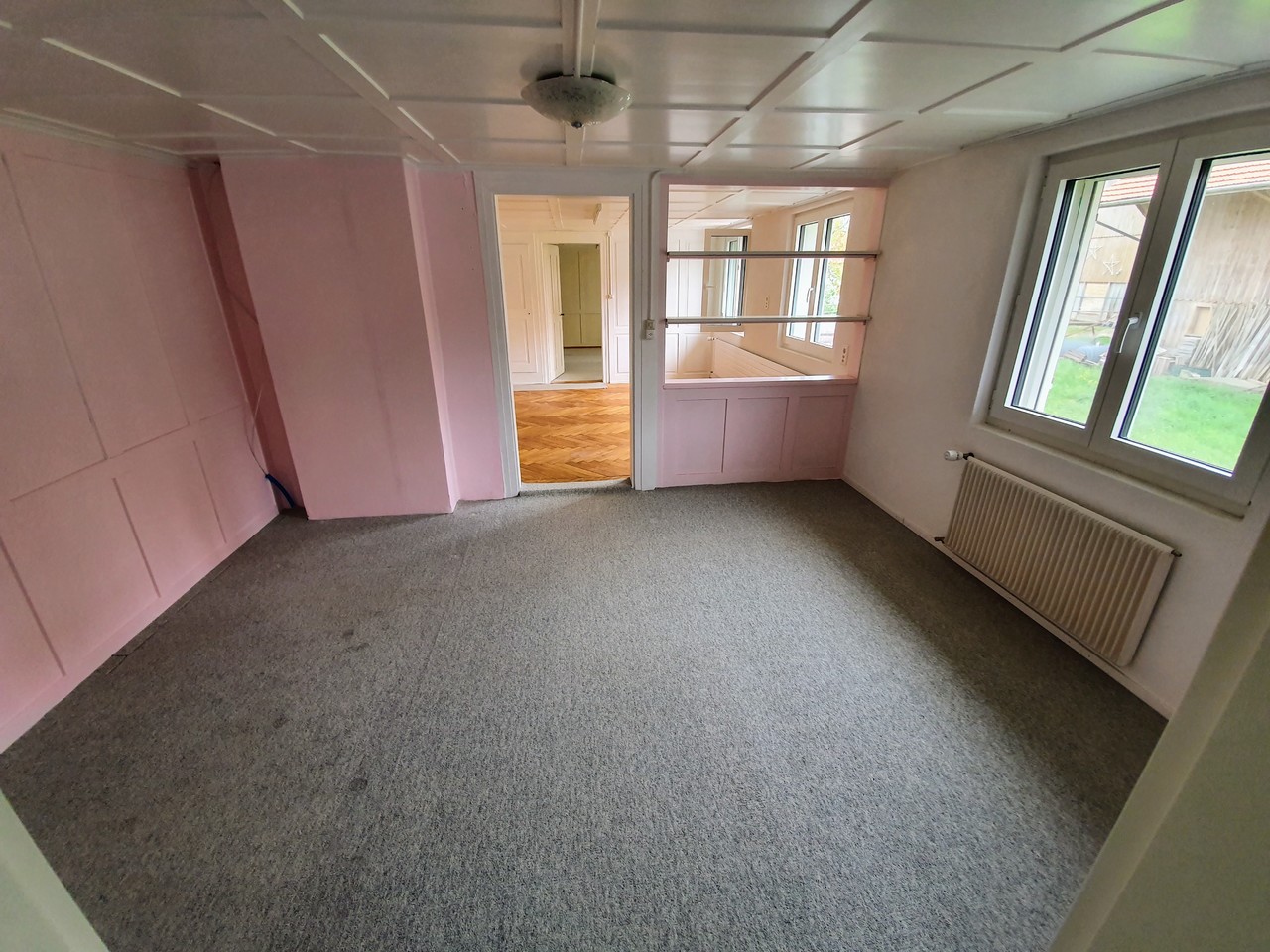 Leerer Raum mit rosa Wandverkleidung und Teppichboden