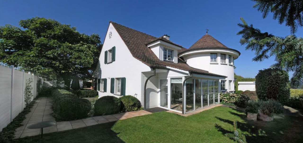 Außenansicht eines gepflegten Einfamilienhauses mit Rundturm und Wintergarten