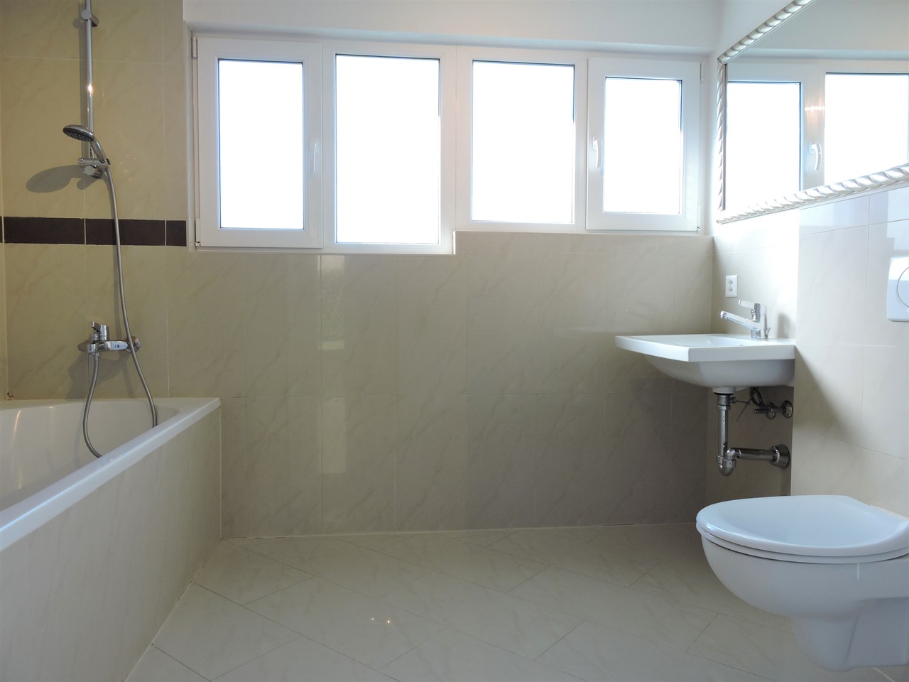 Helles Badezimmer mit Badewanne, Fensterband und Wand-WC