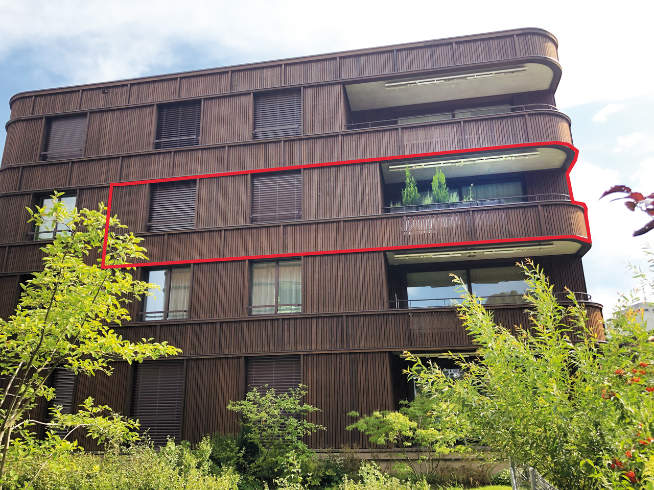 Modernes Mehrfamilienhaus mit Holzfassade und Balkon