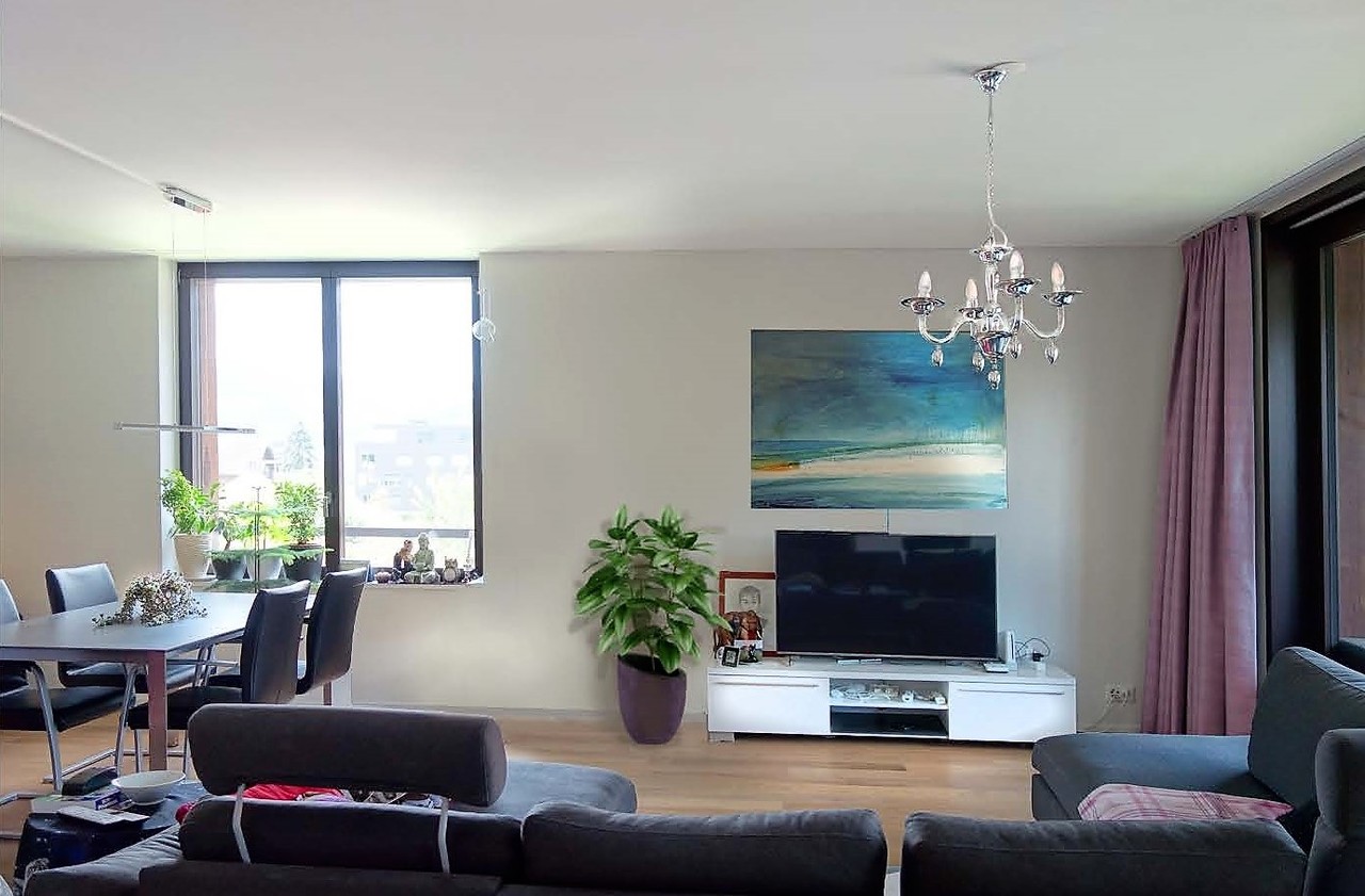 Heller Wohn- und Essbereich mit großem Fenster und TV-Wand