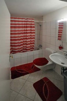 Kleines Badezimmer mit Badewanne und rotem Vorhang