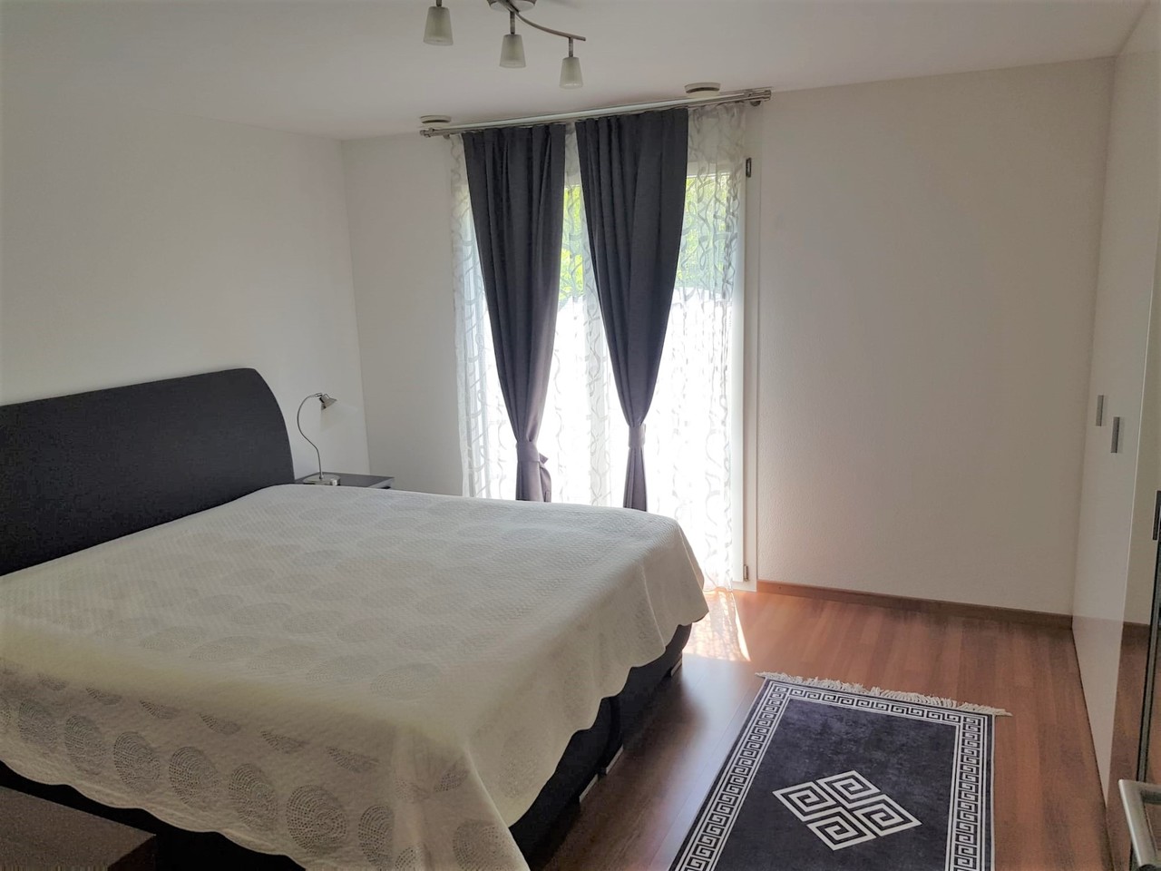 Helles Schlafzimmer mit Bett und Balkon-/Fenstertür