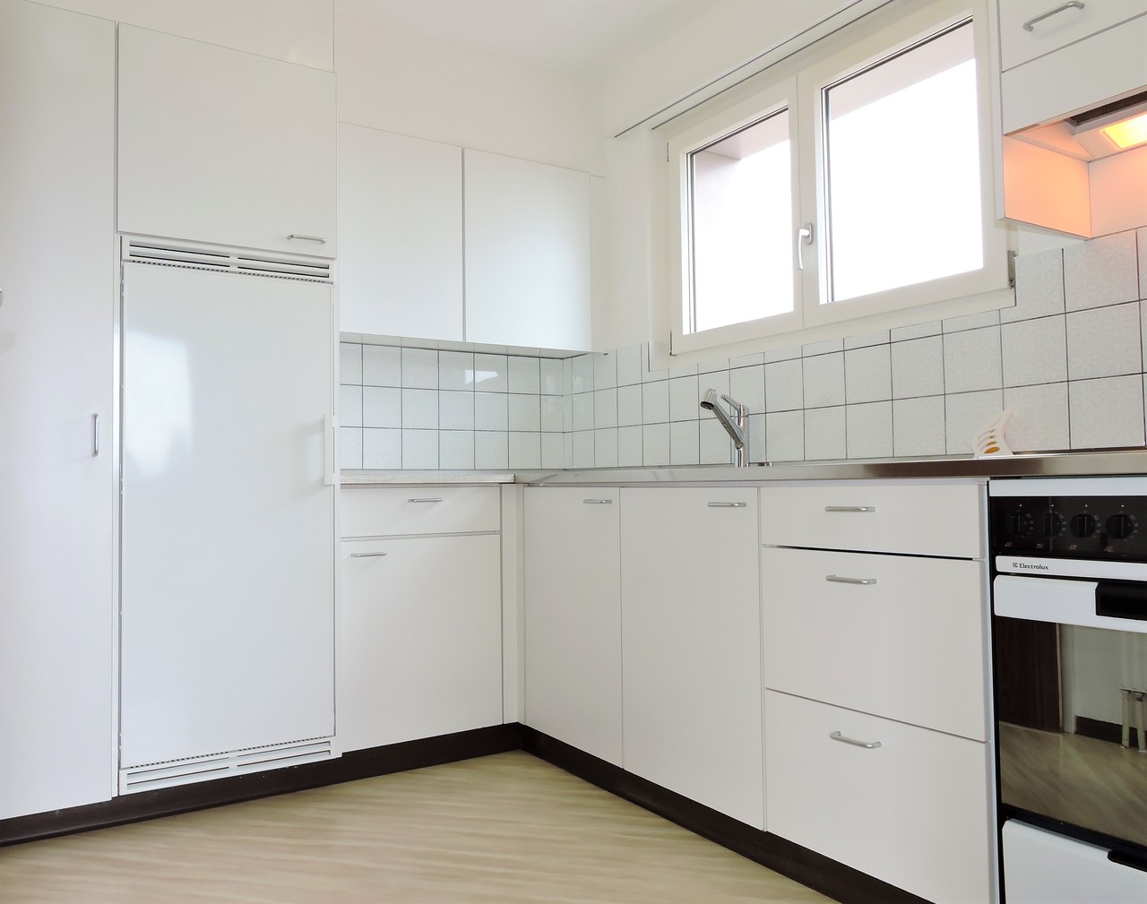 Helle, weiße Einbauküche mit Fenster