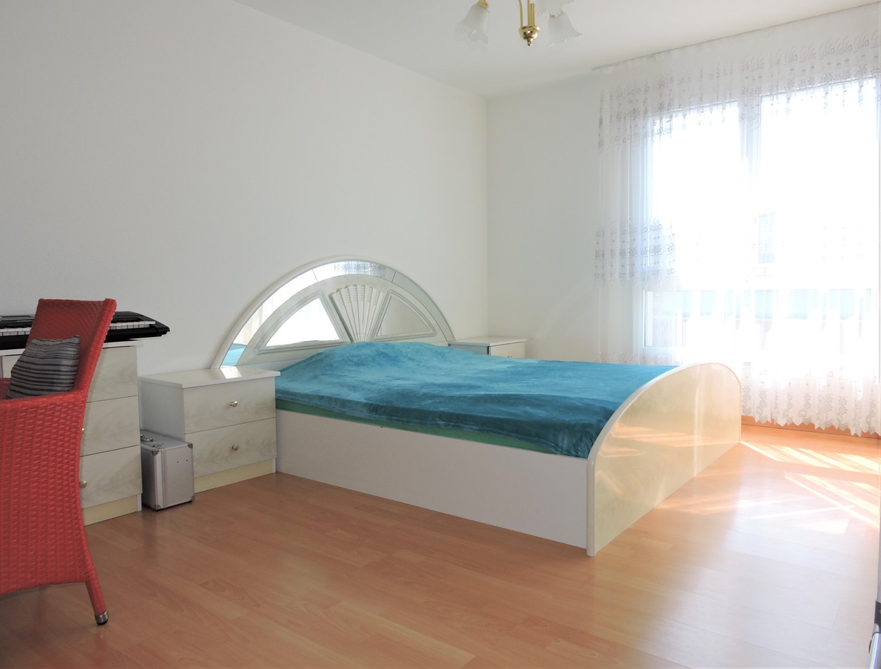 Helles Schlafzimmer mit Einzelbett und großem Fenster