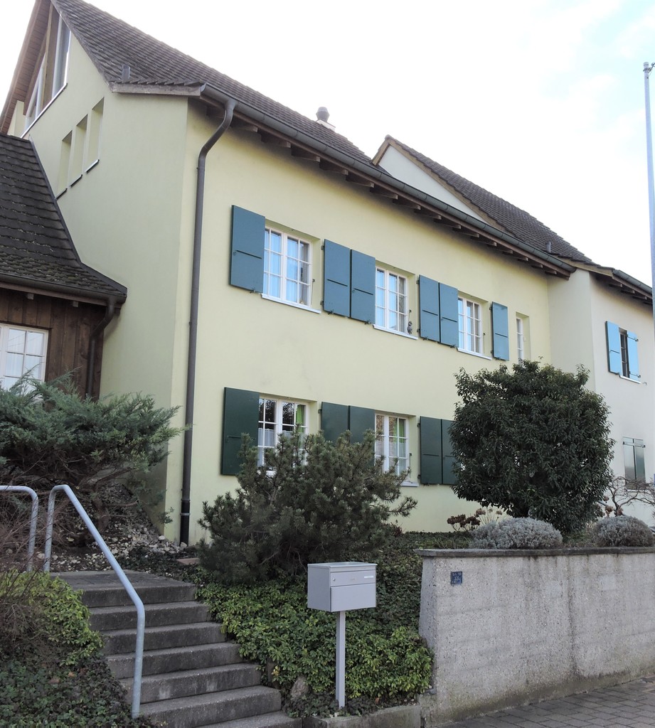 Mehrfamilienhaus mit Satteldach und grünen Fensterläden