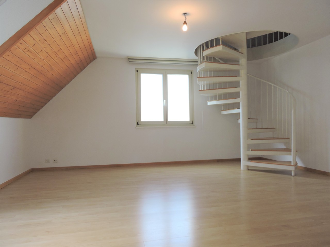 Heller Raum mit Wendeltreppe und Dachschräge