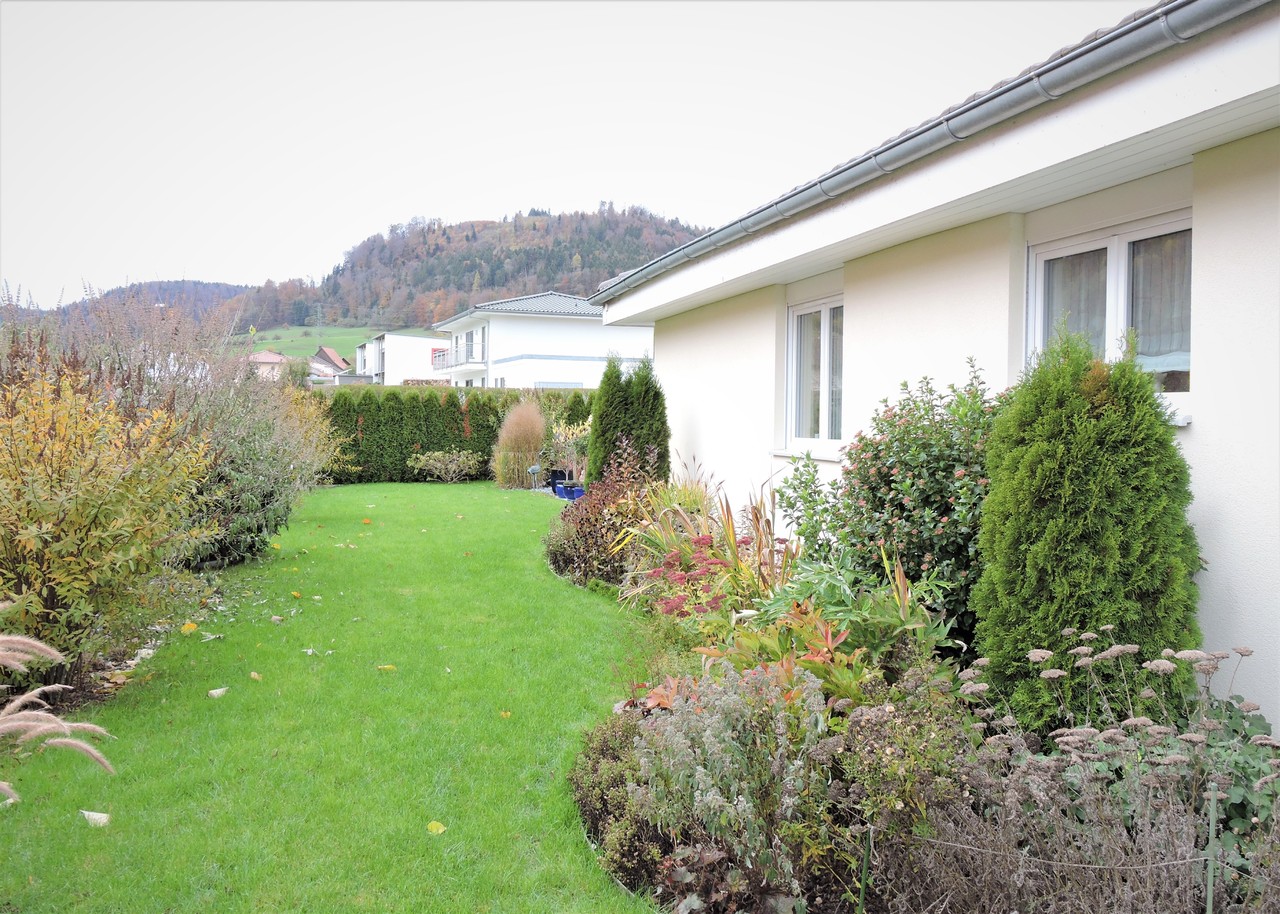Gepflegter Garten mit Hausfassade und Bergblick