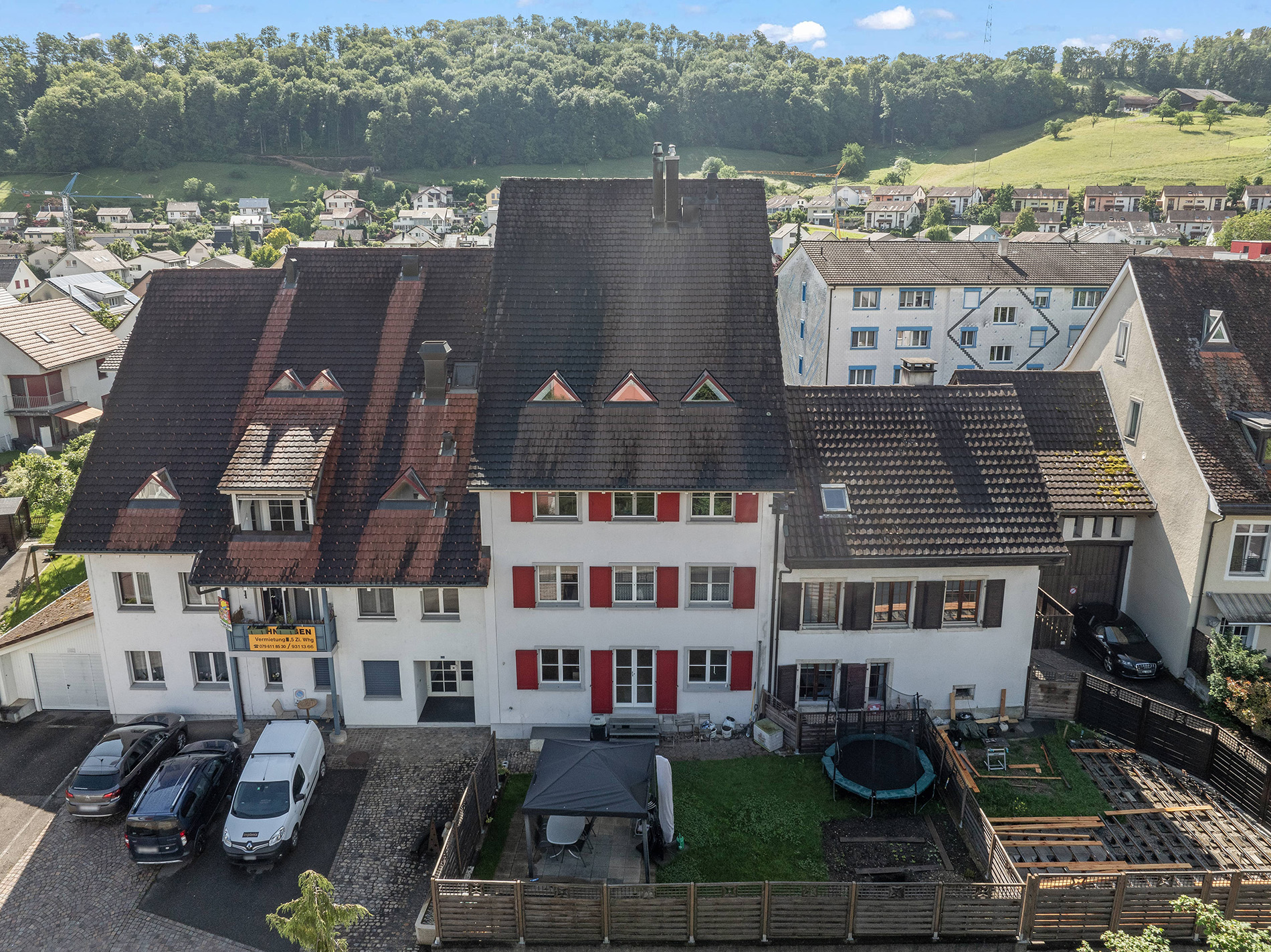 Drohnen-/Hochwinkelansicht von Wohnhäusern mit Garten und Hügellandschaft