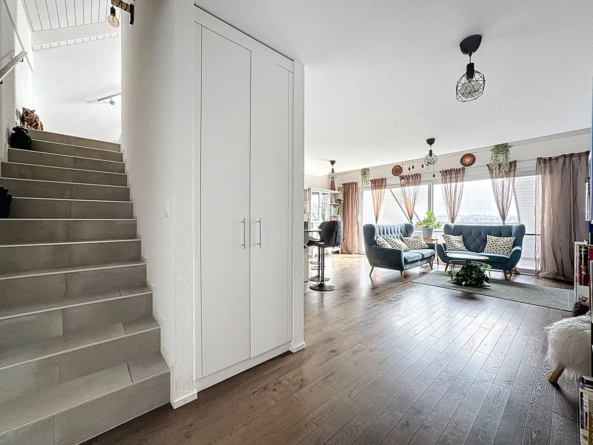 Offener Wohnbereich mit Treppe und Fensterfront