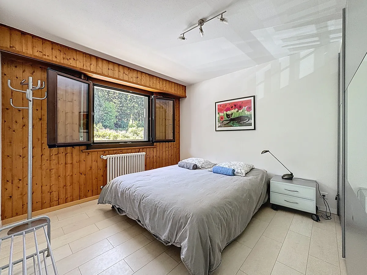 Schlafzimmer mit Holzpaneelen und Blick ins Grüne