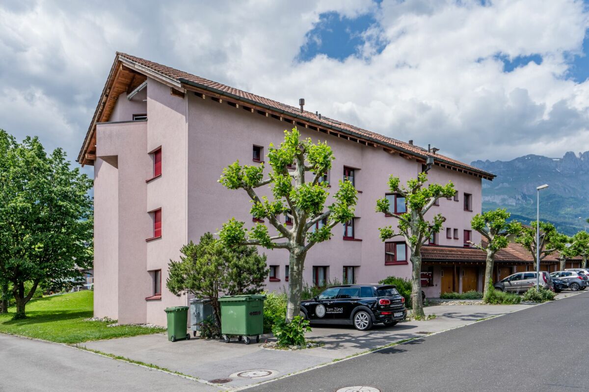 Mehrfamilienhaus mit Bergkulisse und Straße