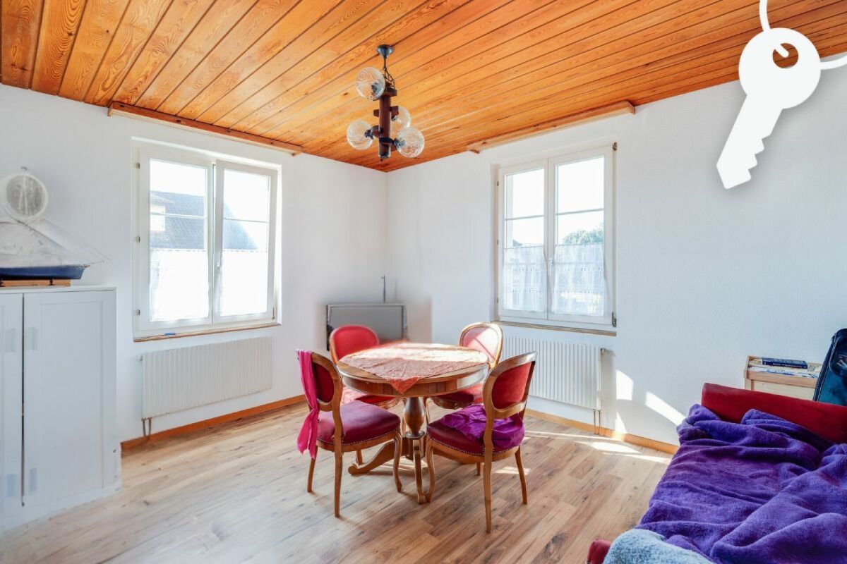 Heller Wohnraum mit Holzbalkendecke und kleinem Essbereich